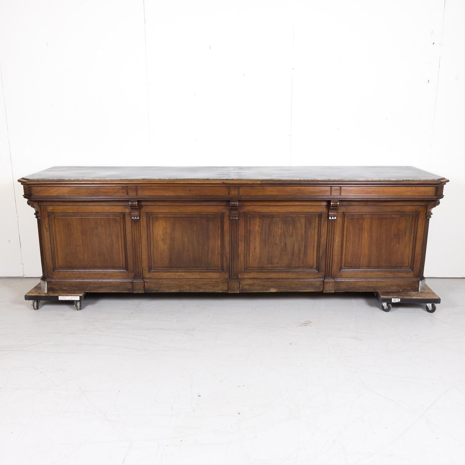 19th century French work counter handcrafted in Normandy of solid walnut with oak drawers, circa 1880s. This impressive counter, from a boutique in Deauville, a seaside resort on the Côte Fleurie, is a little over 10 feet long and features a newly