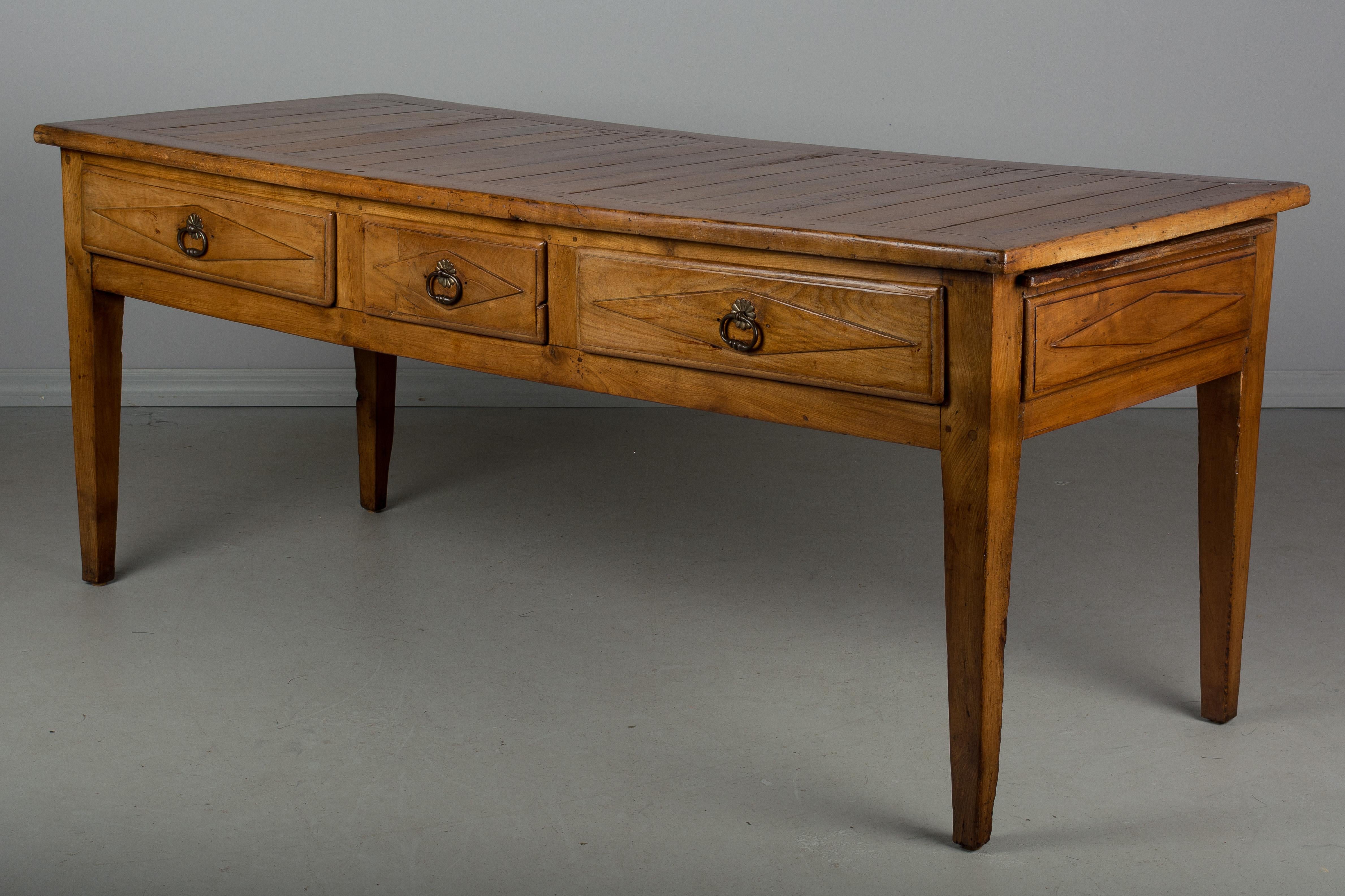 A 19th century, French Country table de Gibier from Normandy made of solid cherry. This was a hunt table for wild game and has three dovetailed drawers and a long pull-out cutting board. Finished on the back with faux drawers to match the front.