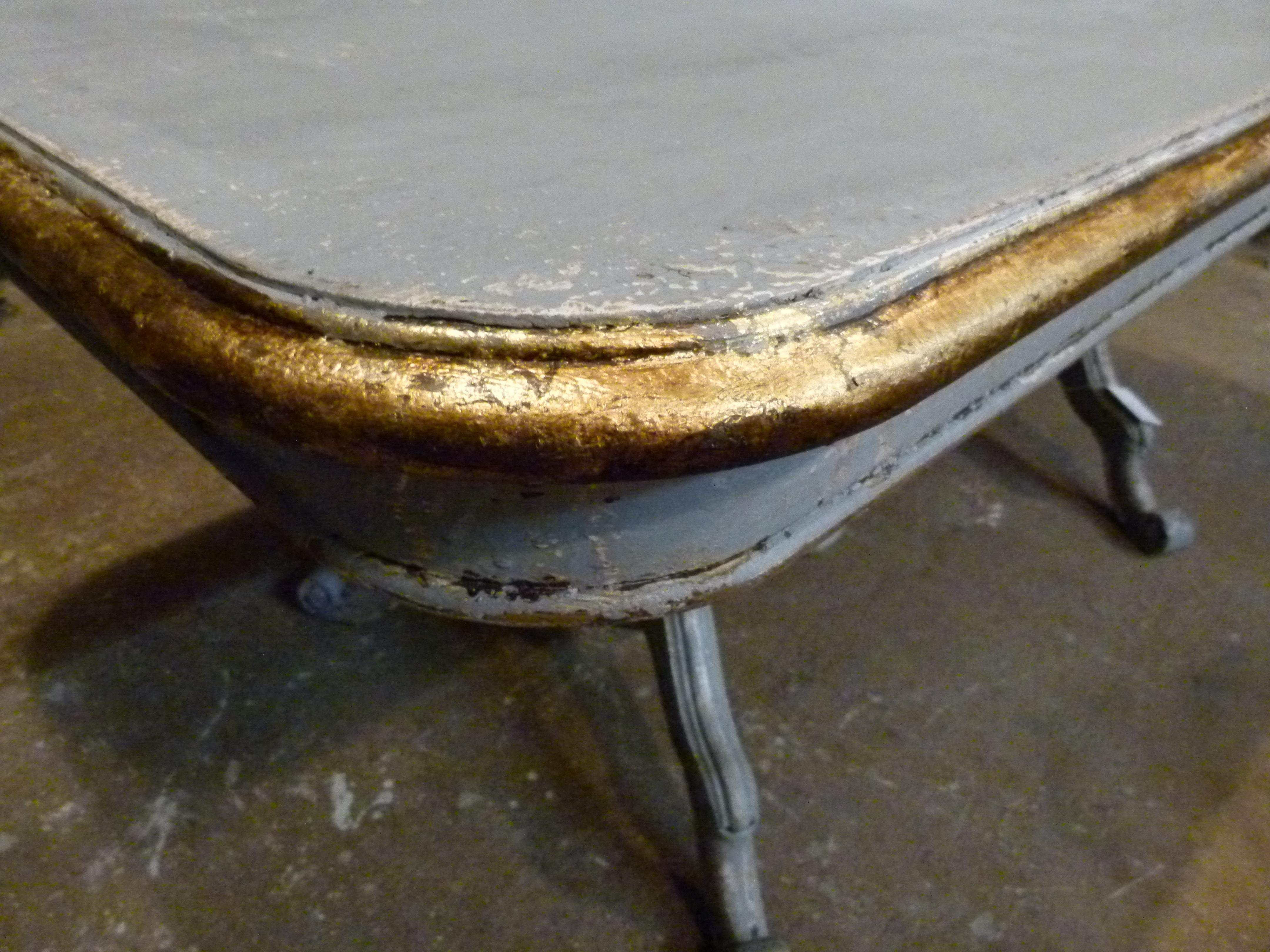 19th century French table with a grey color patina.
The table board is with rounded corners and a gold painted profile. Table legs are also decorated with gold and have the same patina color.
