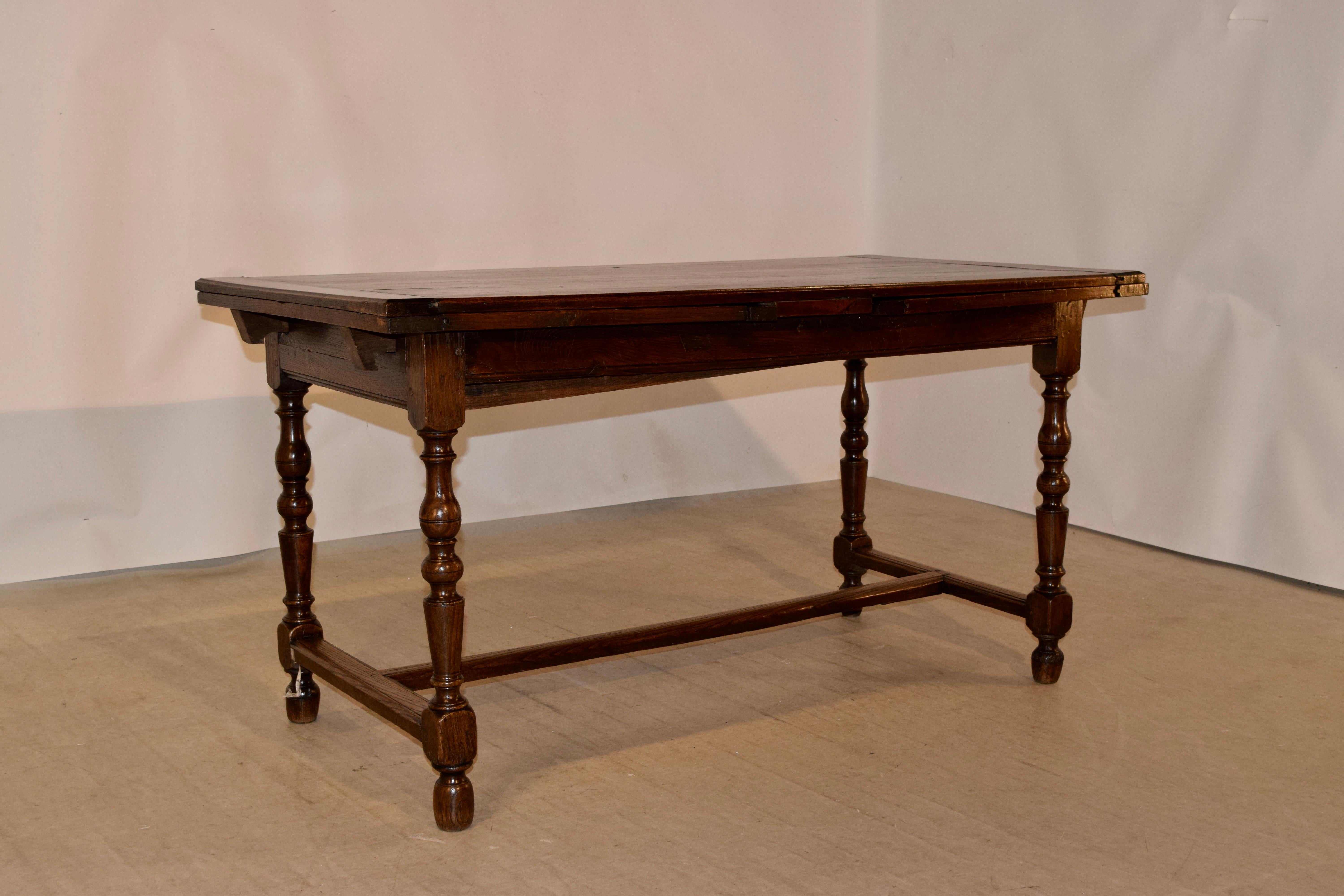 19th century French tavern drawleaf made from oak. The top extends to measure 106.25 inches in length! When closed, it measures 57 inches, for easy placement in any room. The top is simple and has banded ends to help with shrinkage, over a simple