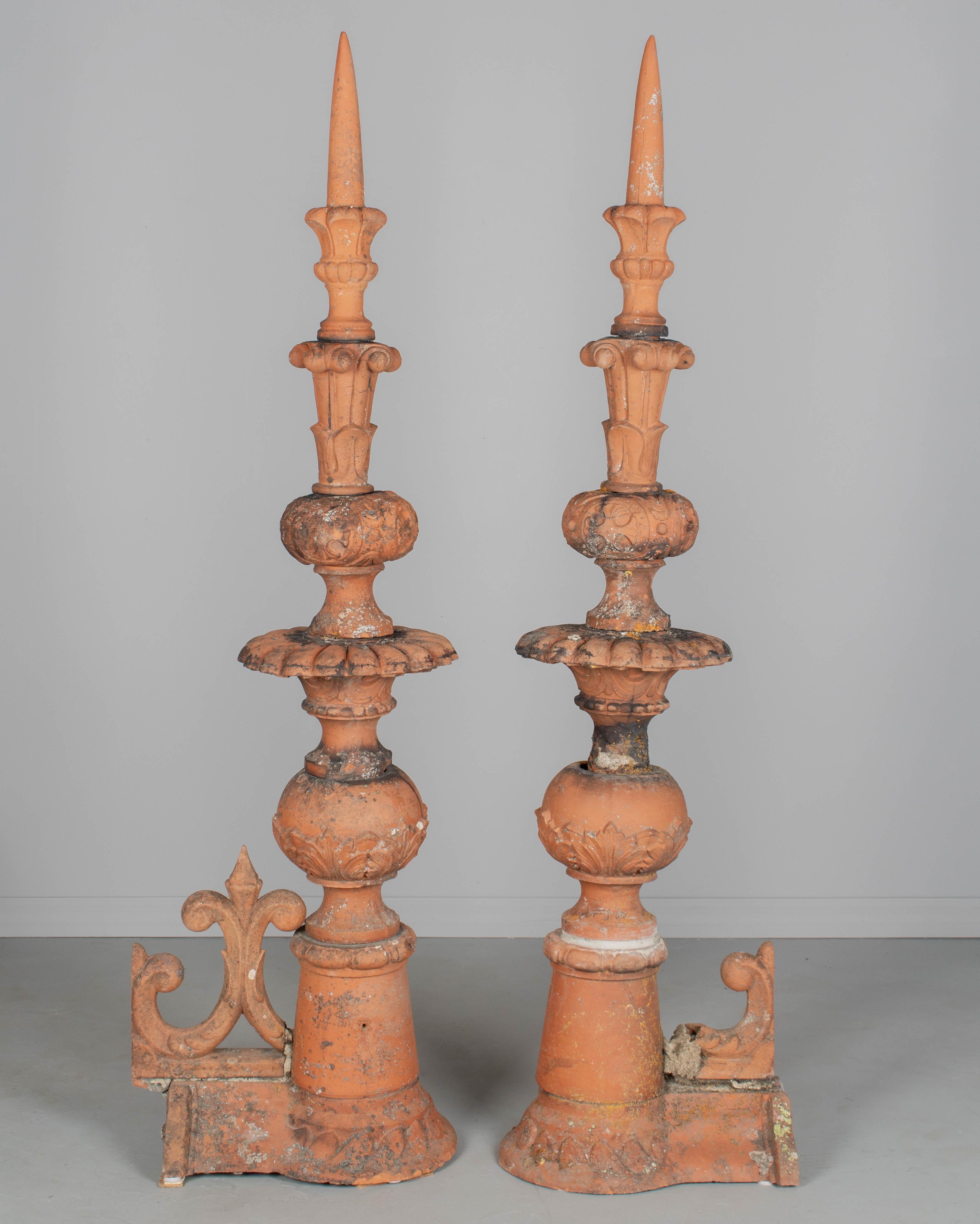 A pair of 19th century terracotta decorative roof finials from a French chateau. Included are two tall architectural spires and two salvaged ornamental fleur-de-lis from the roof's ridge. In very good condition with nice old patina and remnants of