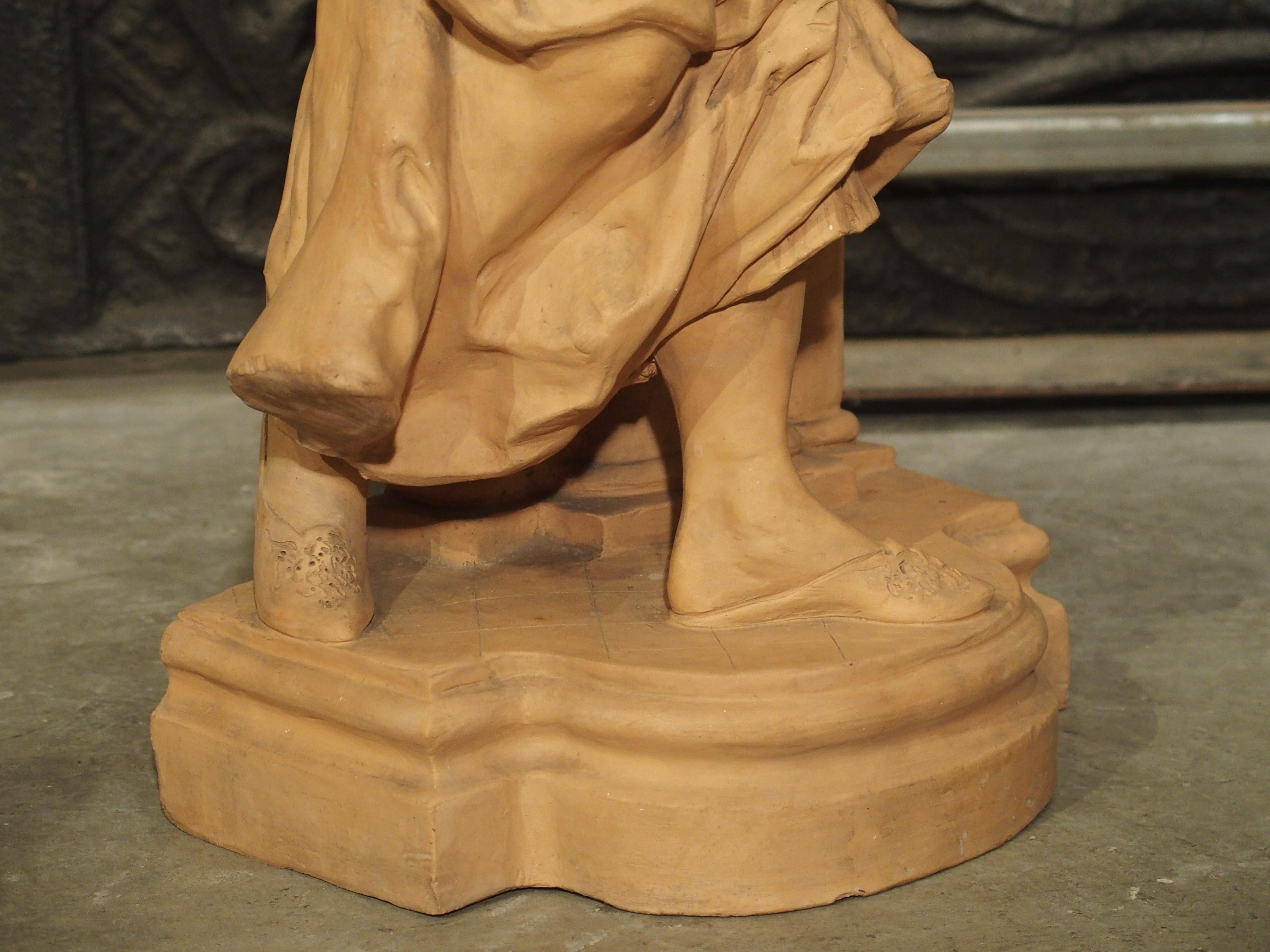 Cette statue en terre cuite bien détaillée d'une femme remplissant une cruche d'eau date de la fin du XIXe siècle et mesure plus de 30 pouces de haut. La femme tient une cruche sous le bec d'une fontaine ; le bec est représenté par un mascaron de