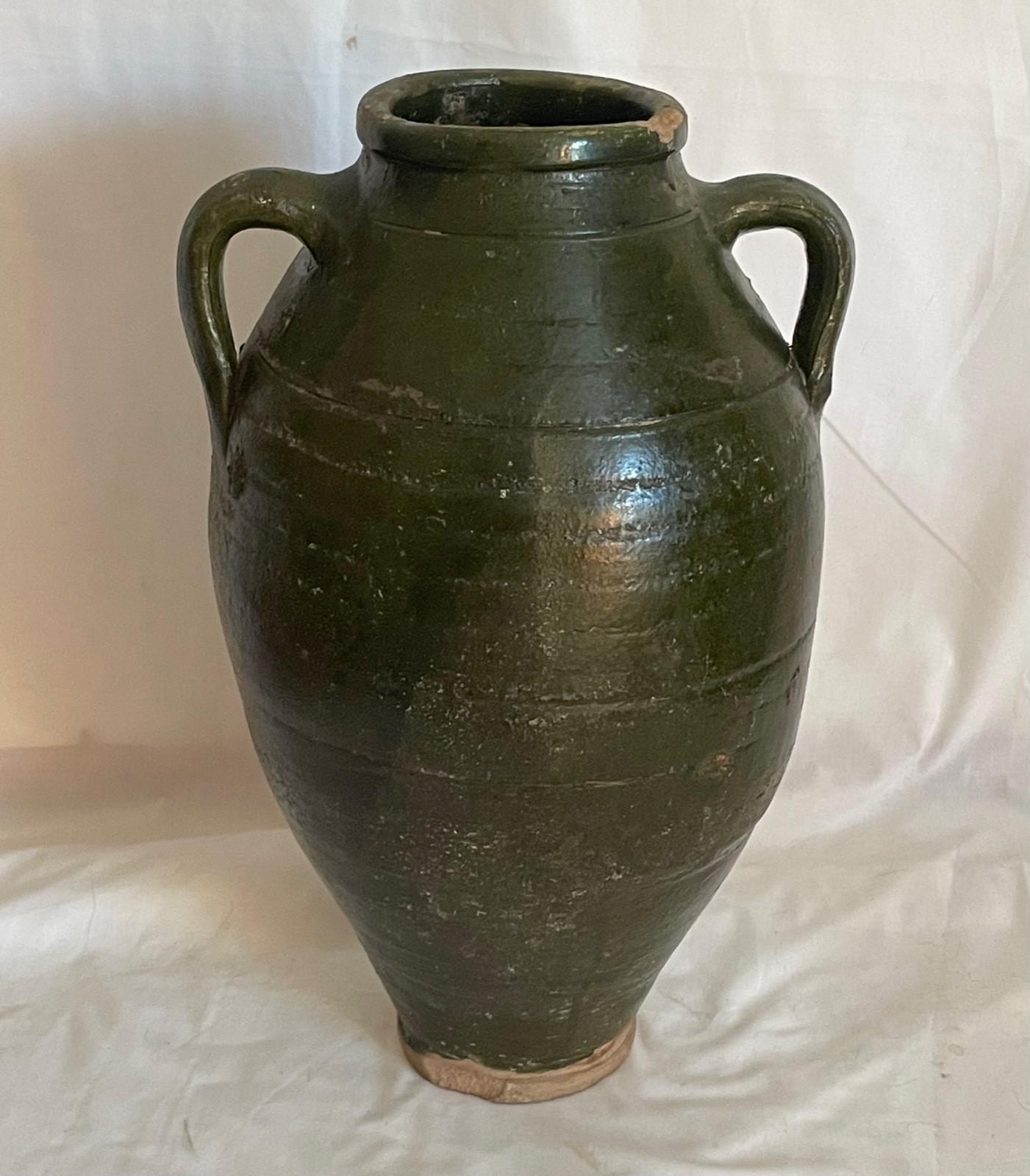 19th Century French terracotta amphora olive jar

French provincial double handle amphora vessel with dark green glaze from the 19th century. The terracotta jug features a green glazed body with a nicely distressed patina. Probably created for the