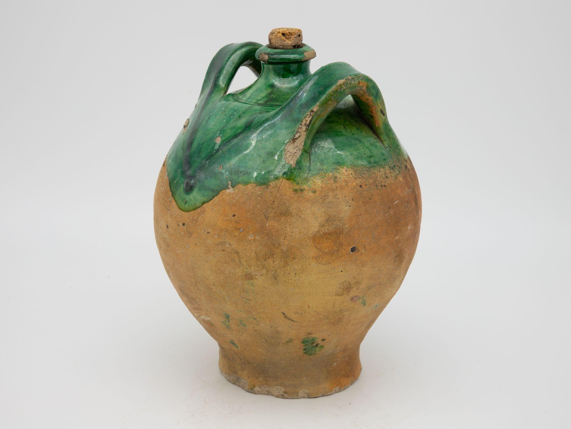 A late 19th century terracotta confit pot from Southwest France. The pot has its original cork and shows two handles with a traditional green glaze. Wear consistent for age and use.