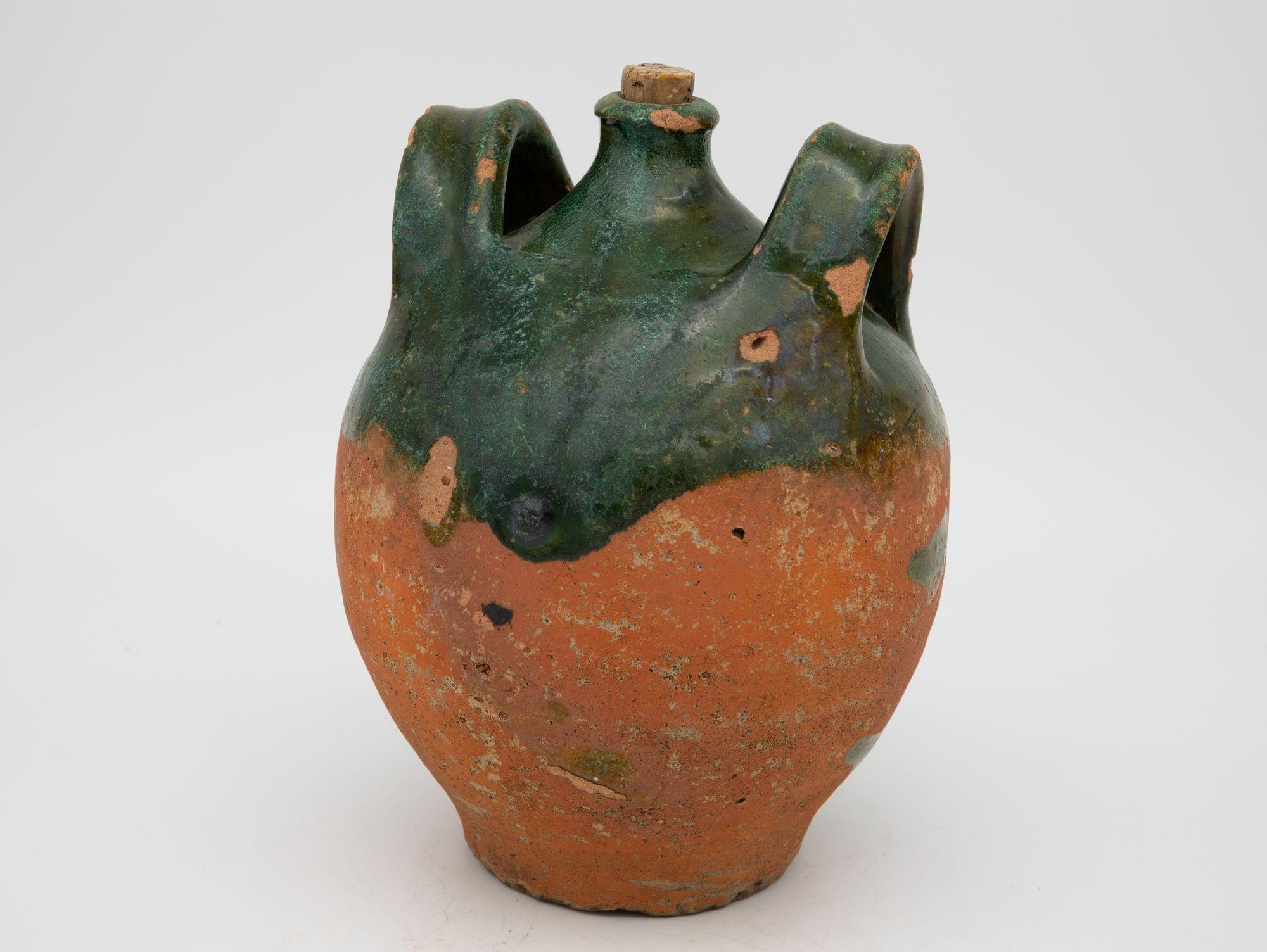 A late 19th century terracotta confit pot from Southwest France. The pot has its original cork and shows two handles with a traditional green glaze. Wear consistent for age and use.0