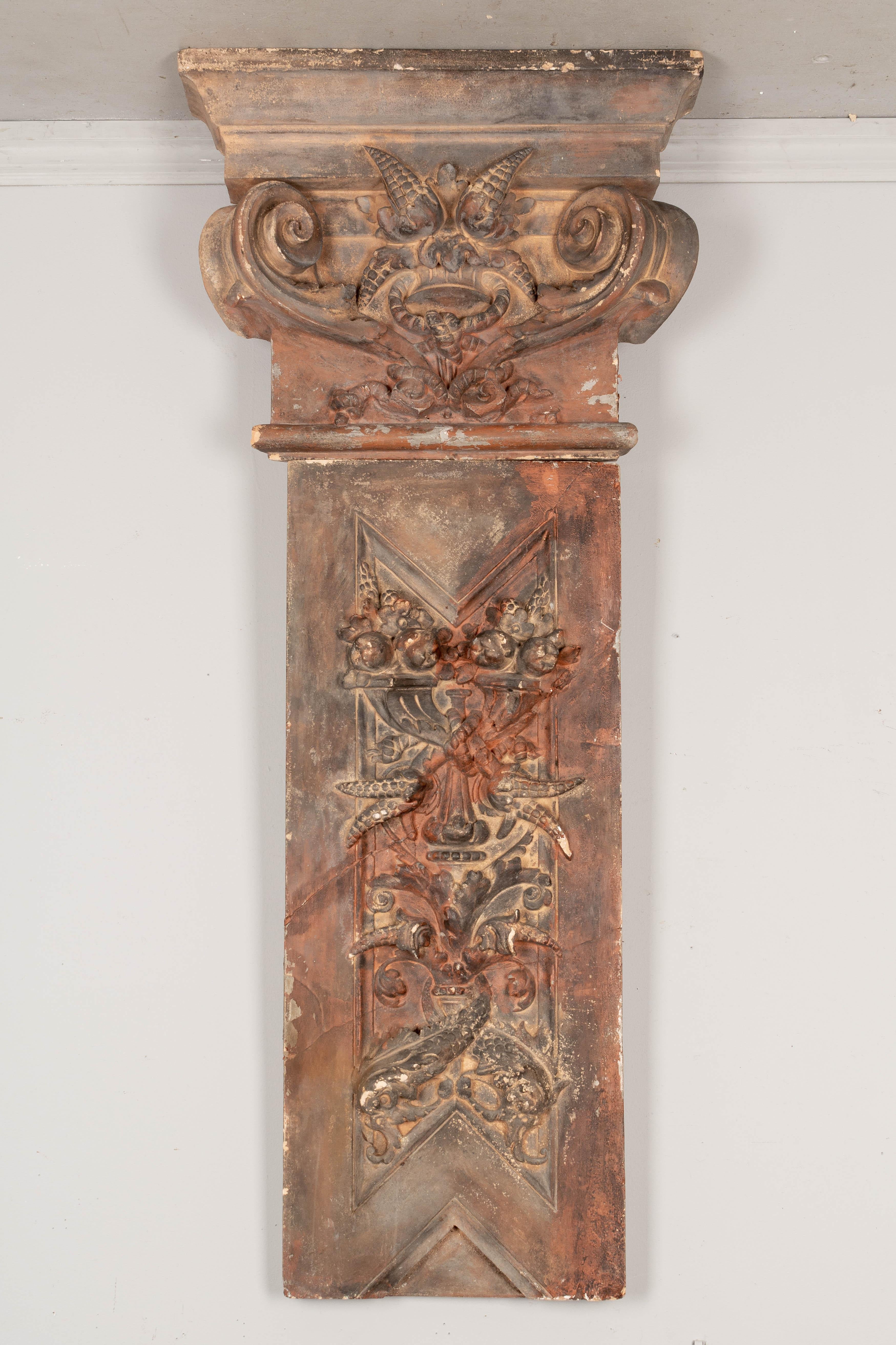 A 19th century French terracotta architectural relief. In two parts, a rectangular plaque and scroll form capital, each with fruits and foliage in three dimensional sculptural relief. Restored cracks and minor losses. A nice decorative design