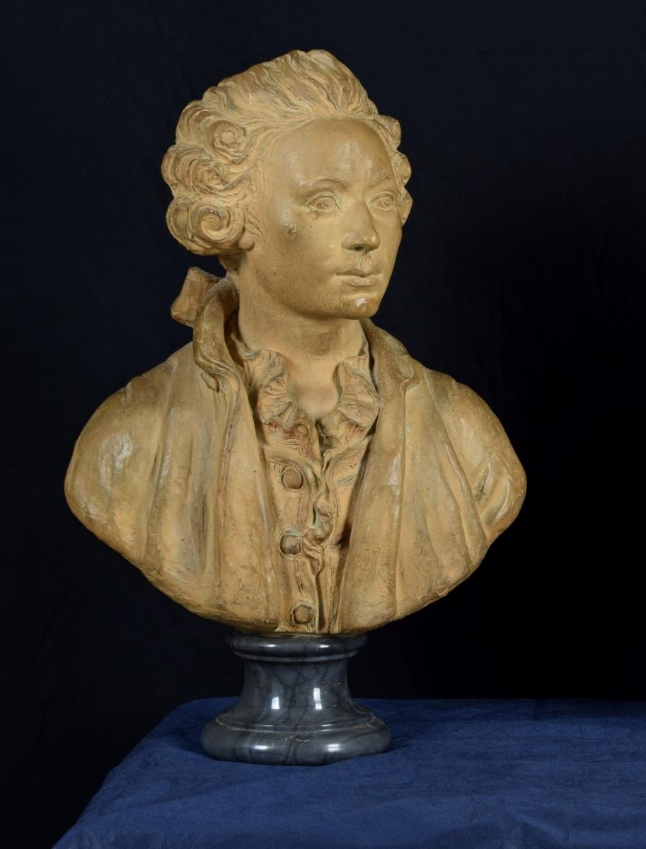 Terracotta bust depicting nobleman, marble base, 19th century, France

The refined bust depicts a nobleman dressed according to the fashion of the mid-eighteenth century in France. The man wears his hair tied in a tight tail by a bow. He wears an