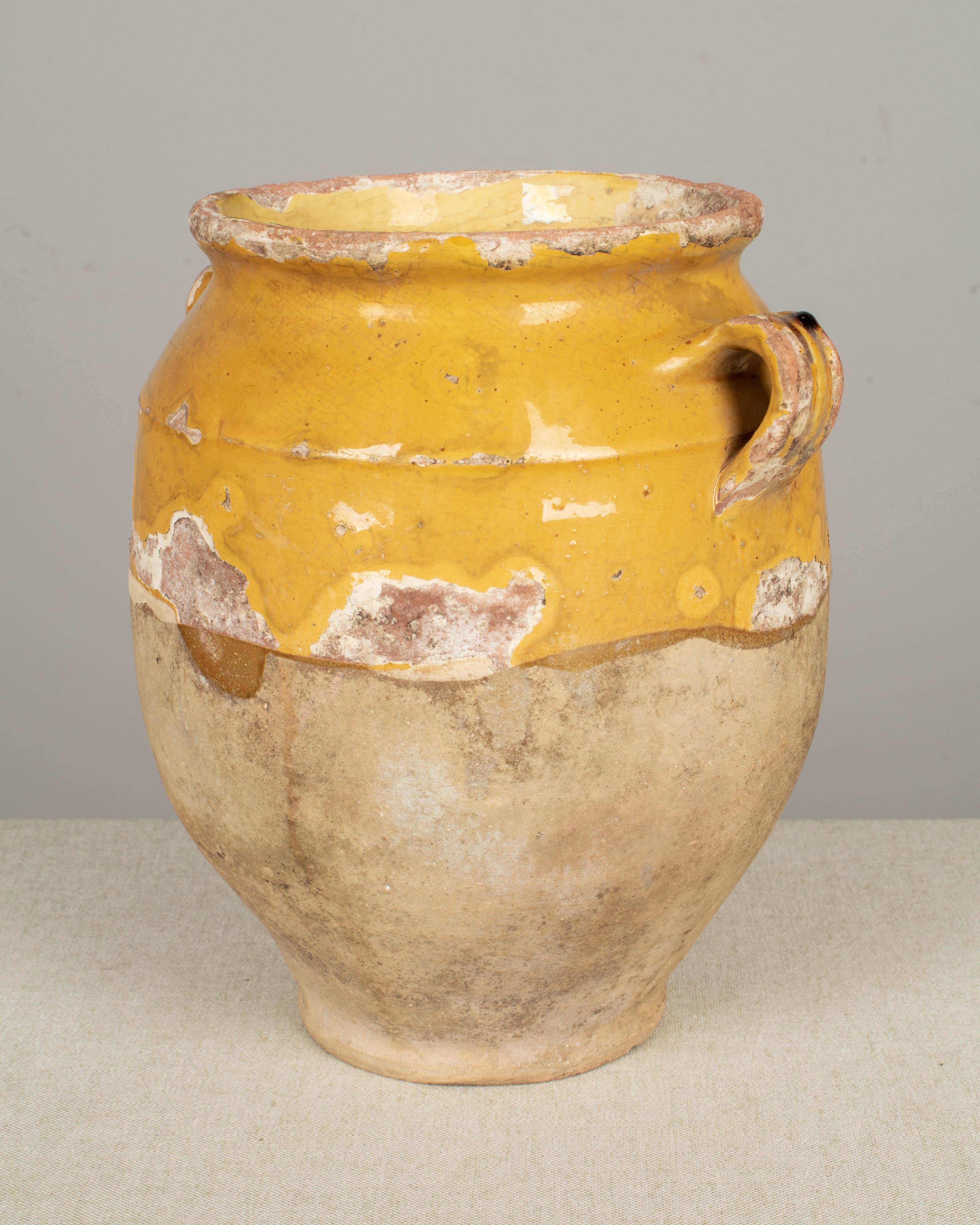 A 19th century earthenware confit pot from the Southwest of France with traditional yellow glaze. Chips and losses to glaze. These ordinary earthenware vessels were once used daily in the French country home and have beautiful rustic glazes of