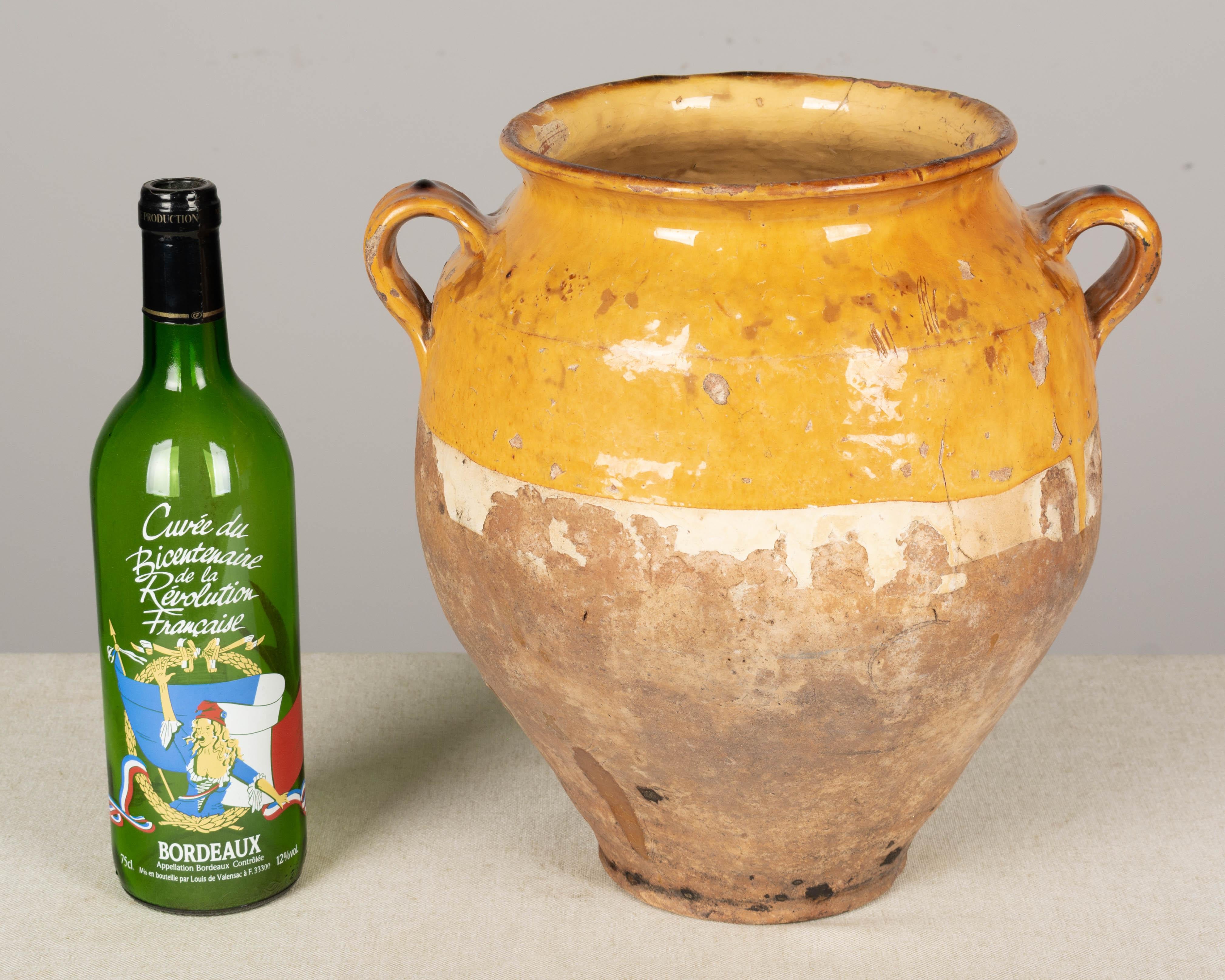 A 19th century earthenware confit pot from the Southwest of France with traditional yellow ochre glaze. Chips, cracks and losses to glaze. These ordinary earthenware vessels were once used daily in the French country home and have beautiful rustic
