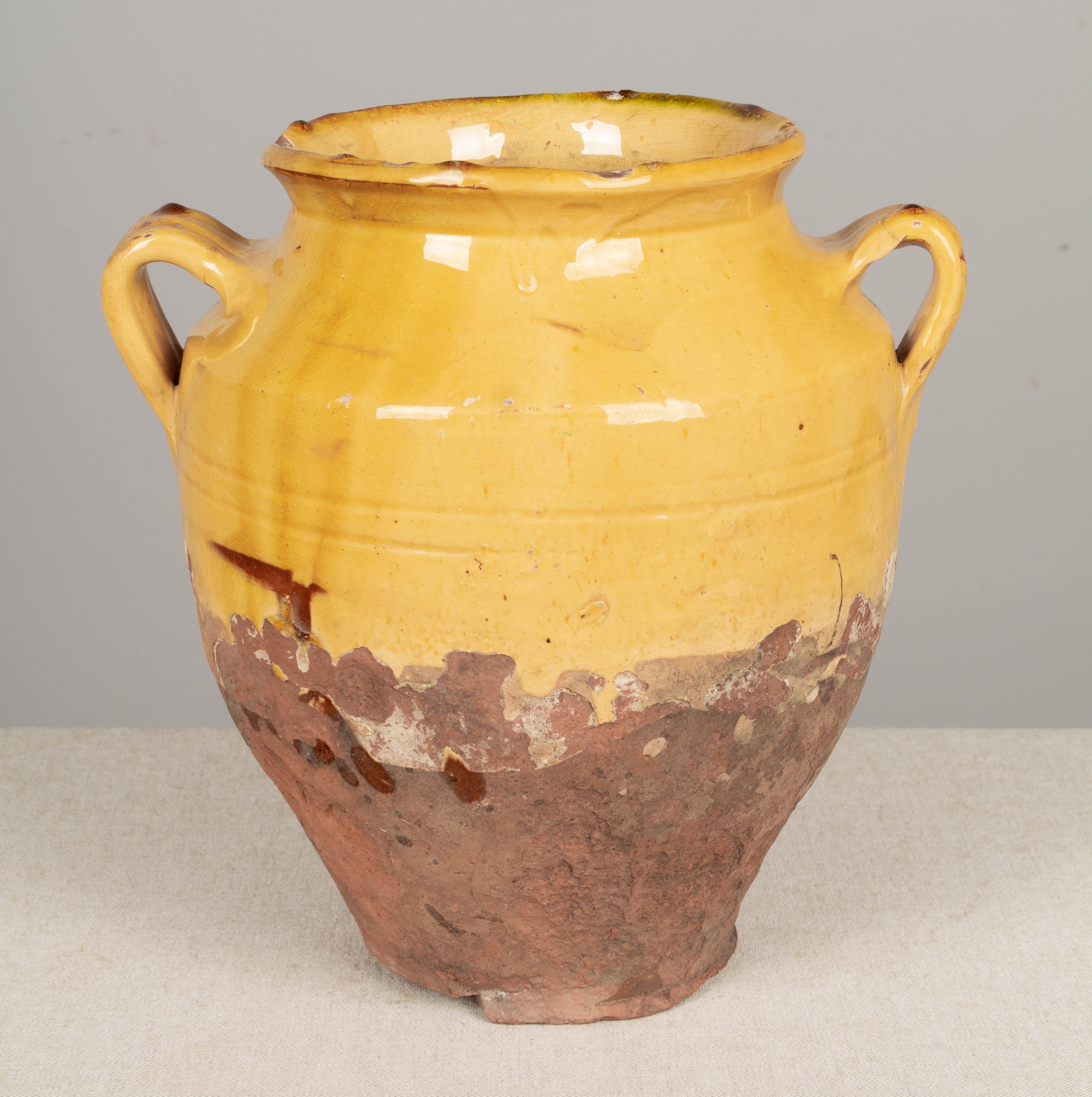A 19th century earthenware confit pot from the Southwest of France with traditional yellow glaze. Chips, cracks and losses to glaze. Large hole in bottom. These ordinary earthenware vessels were once used daily in the French country home and have