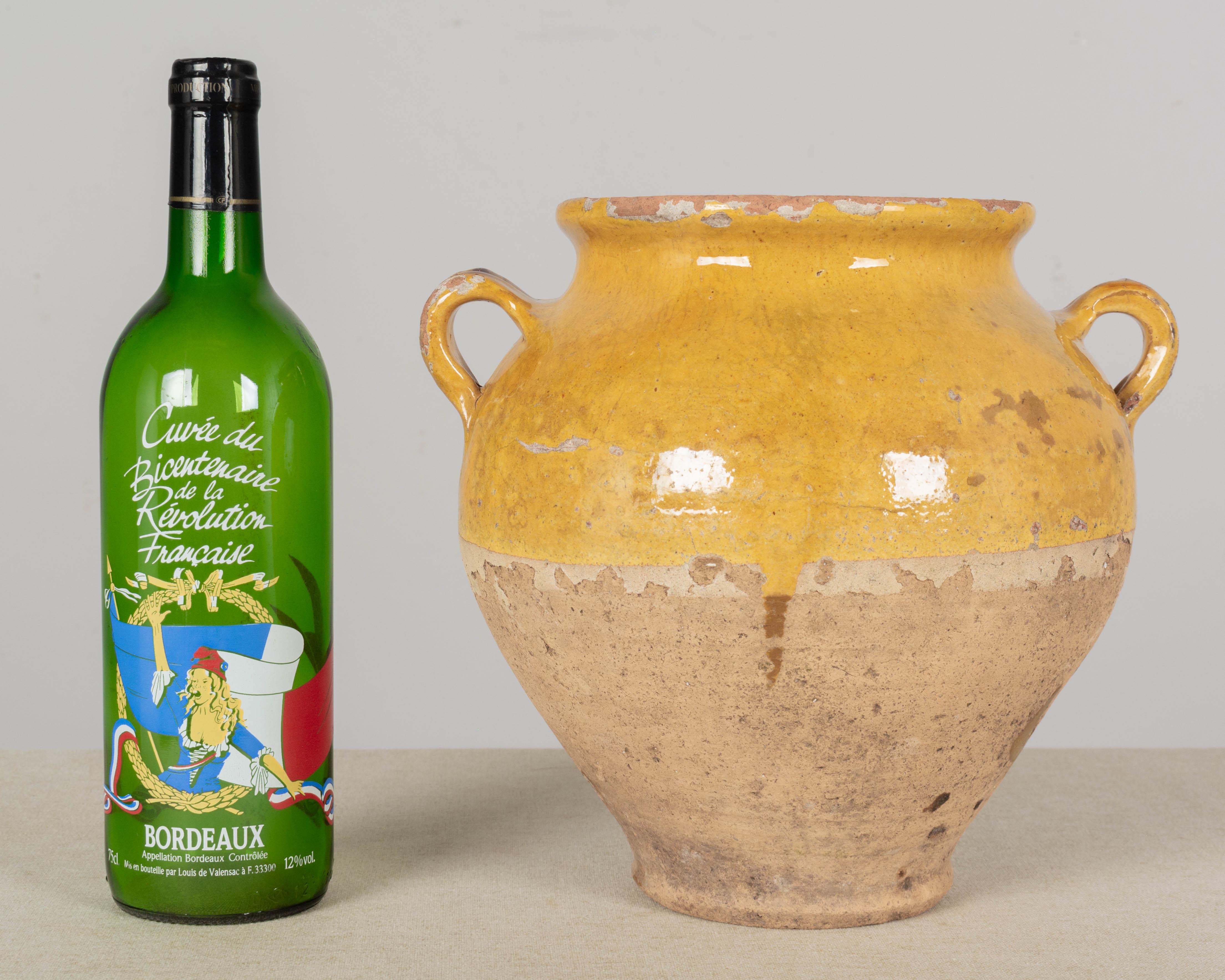 An earthenware confit pot from the Southwest of France with traditional yellow glaze. Some chips and losses to glaze. These ordinary earthenware vessels were once used daily in the French country home and have beautiful rustic glazes of green, ochre