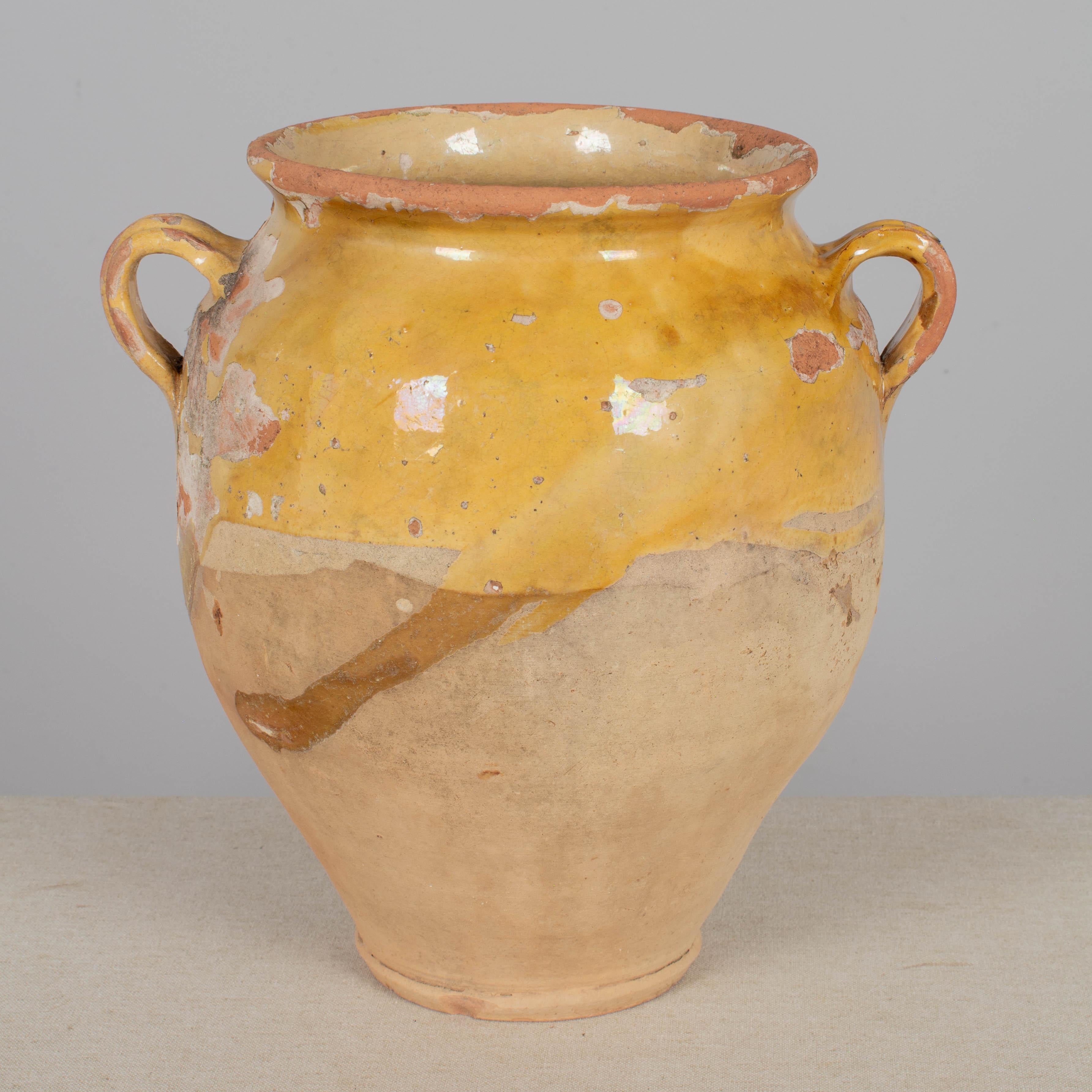 A 19th century French earthenware confit pot with traditional yellow glaze. Small drainage holes in bottom for use as a planter. Some chips and losses to glaze. These ordinary earthenware vessels were once used daily in the French country home and