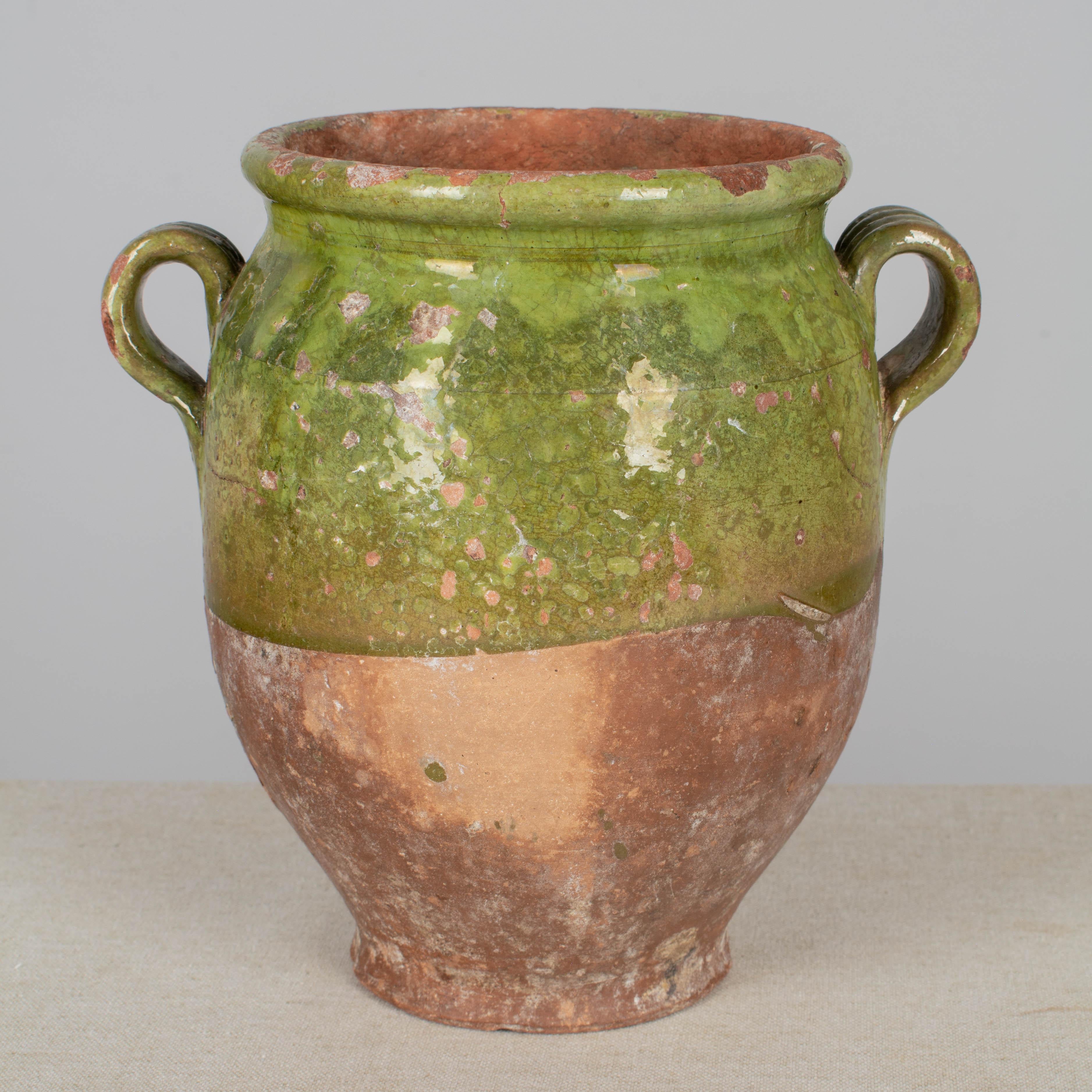 A 19th century French earthenware small confit pot with traditional green glaze. Some chips and losses to glaze. These ordinary earthenware vessels were once used daily in the French country home and have beautiful rustic glazes of yellow, green,