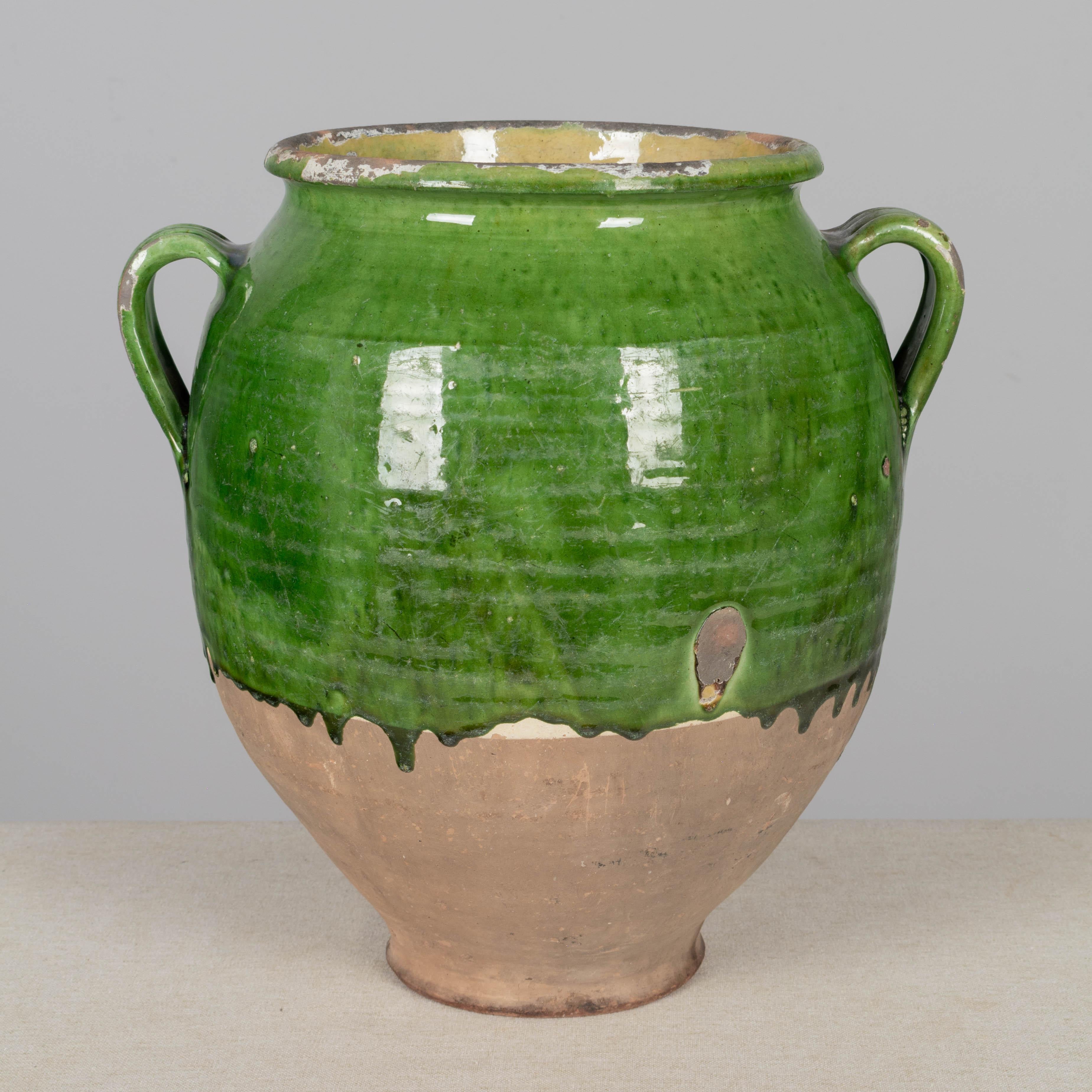 A 19th century French earthenware confit pot with traditional green glaze and pale yellow interior. Some chips and losses to glaze. These ordinary earthenware vessels were once used daily in the French country home and have beautiful rustic glazes