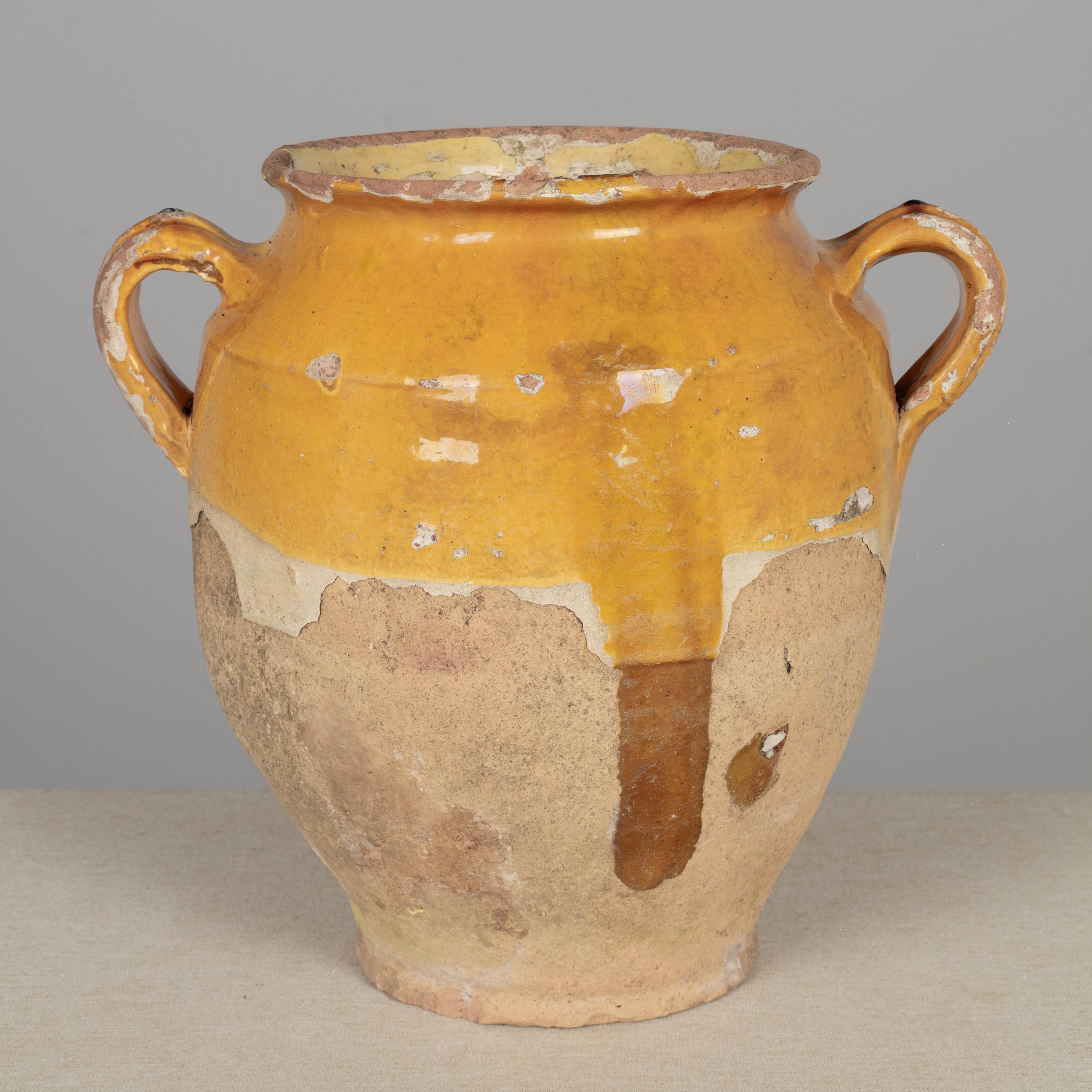 A 19th century French earthenware confit pot with traditional yellow glaze. Small drainage hole in bottom for use as a planter. Some chips and losses to glaze. These ordinary earthenware vessels were once used daily in the French country home and