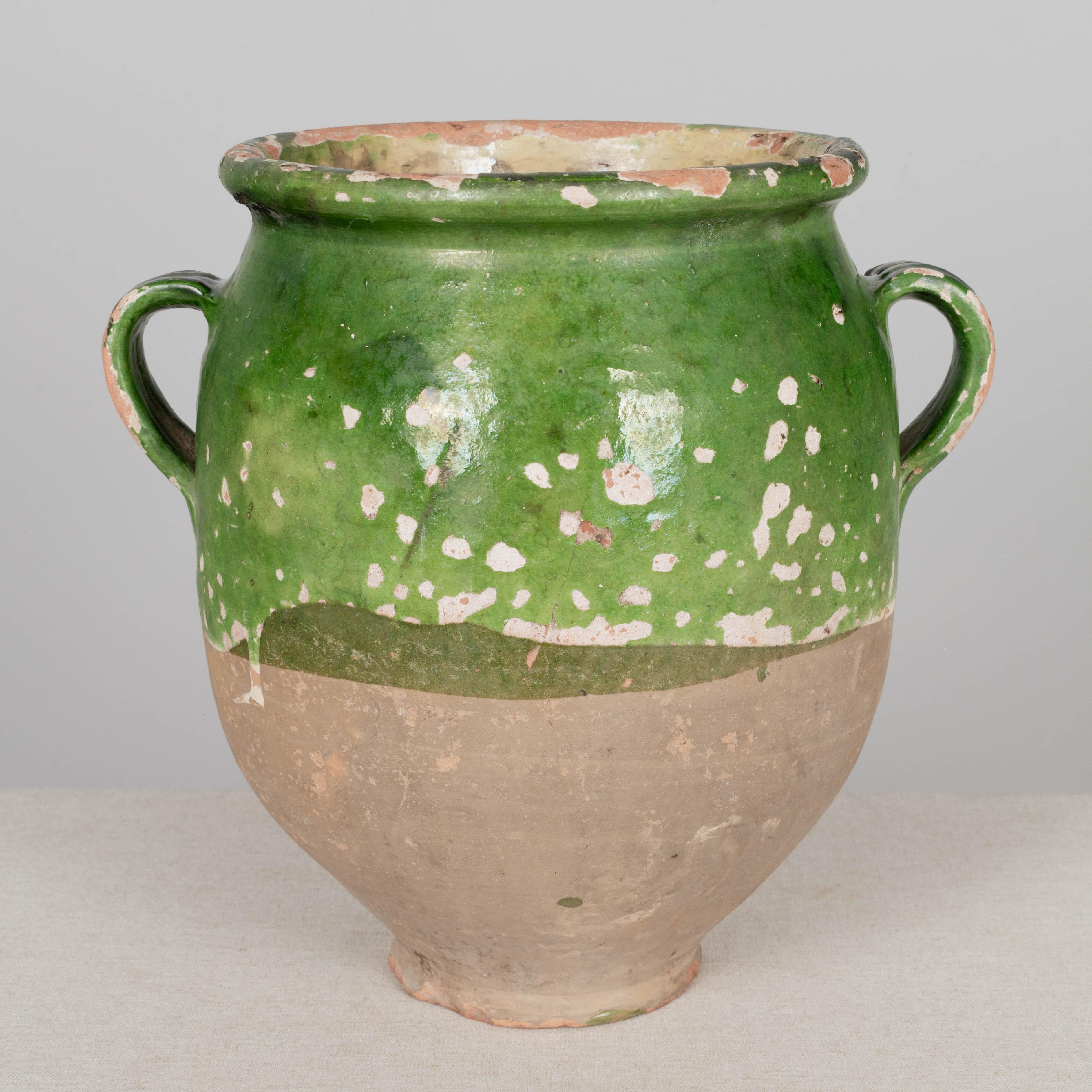 A 19th century French earthenware confit pot with traditional green glaze and pale yellow interior. Some chips and losses to glaze. These ordinary earthenware vessels were once used daily in the French country home and have beautiful rustic glazes