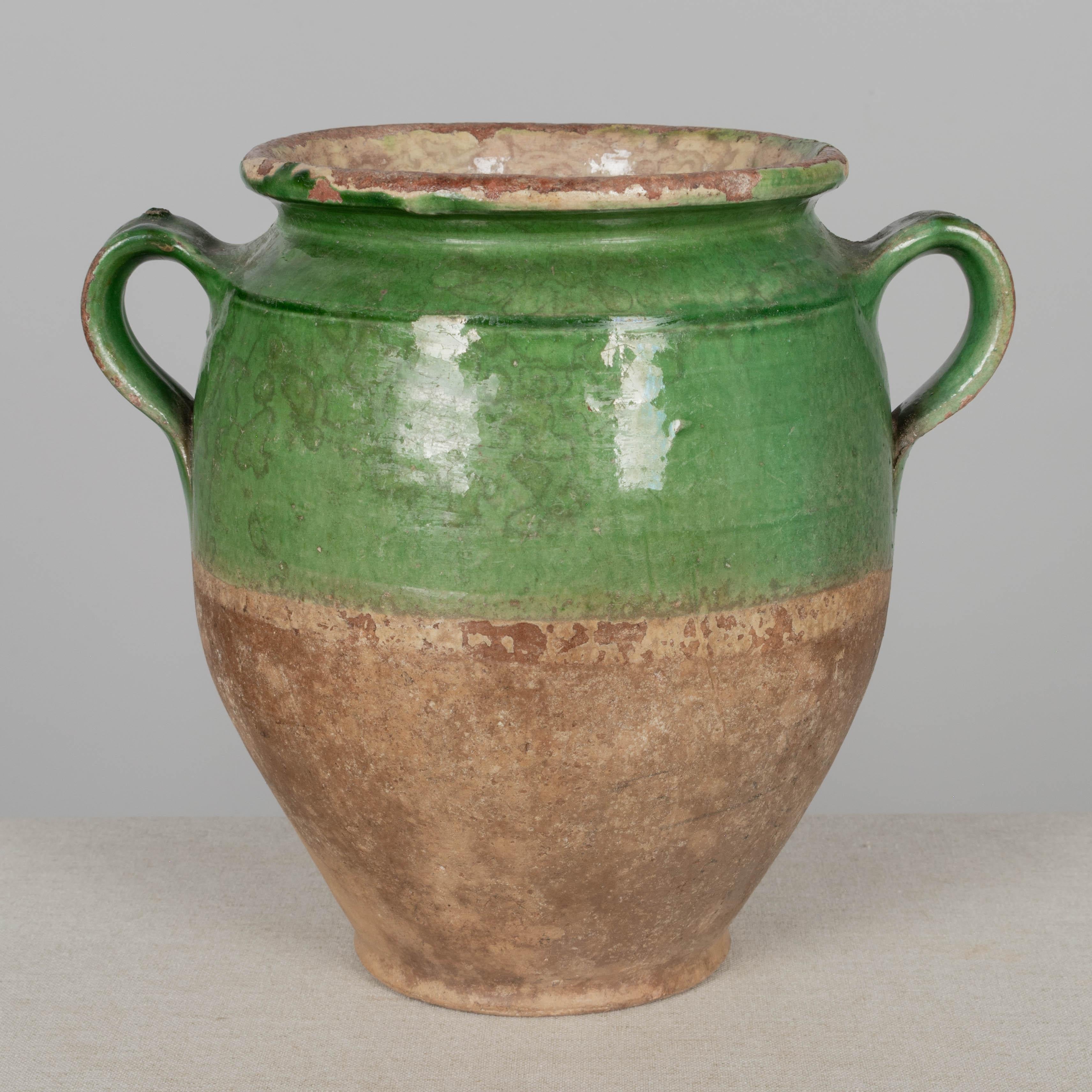 A 19th century French earthenware confit pot with traditional green glaze and pale yellow interior. Nice old patina. Chips and losses to glaze. These ordinary earthenware vessels were once used daily in the French country home and have beautiful