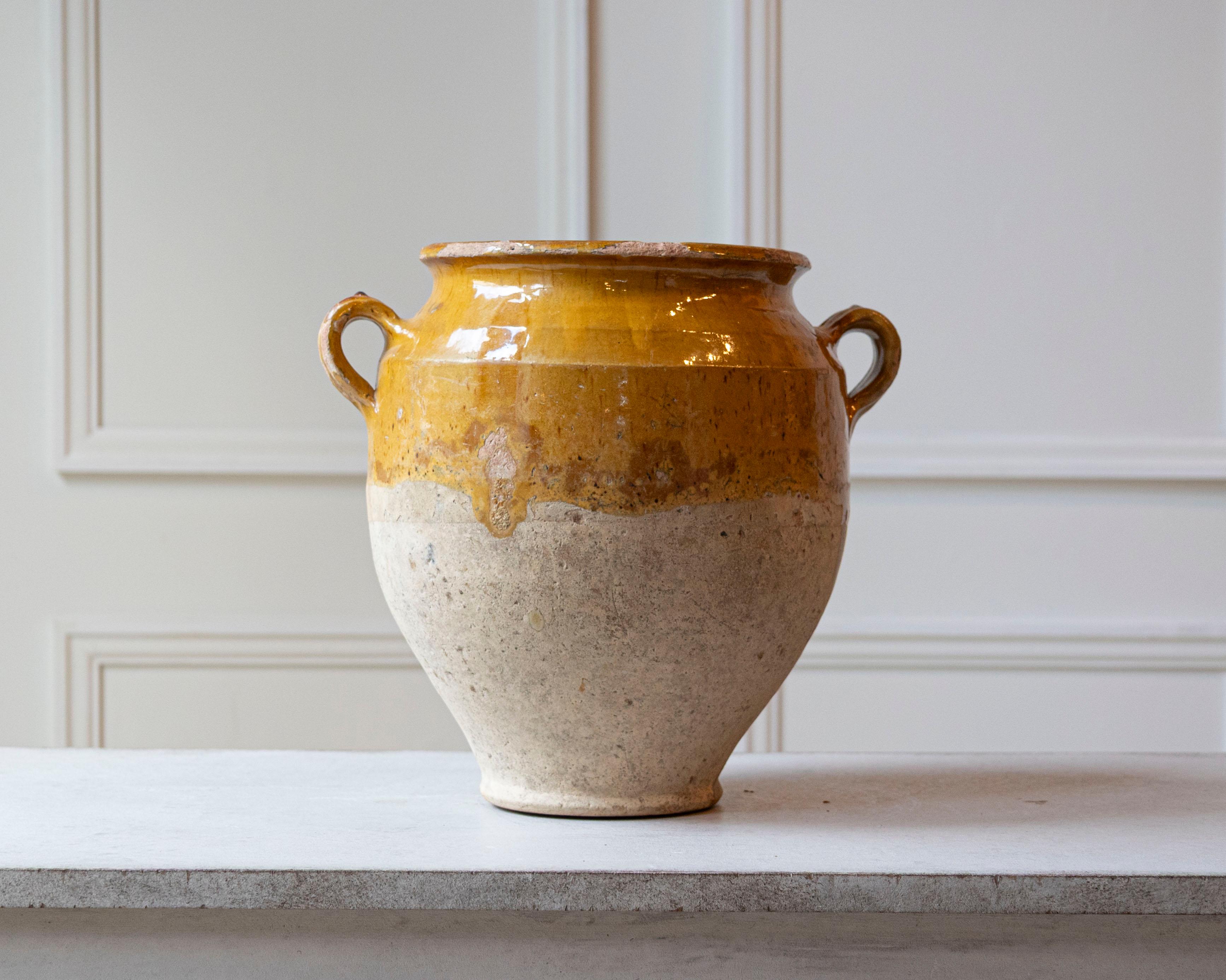 Dieser französische Confit-Topf aus dem 19. Jahrhundert ist ein strahlendes Beispiel für alltägliche bäuerliche Töpferware, die durch Zeit und Patina aufgewertet wurde. Dieses aus Südfrankreich stammende, handgegossene Terrakotta-Gefäß weist im