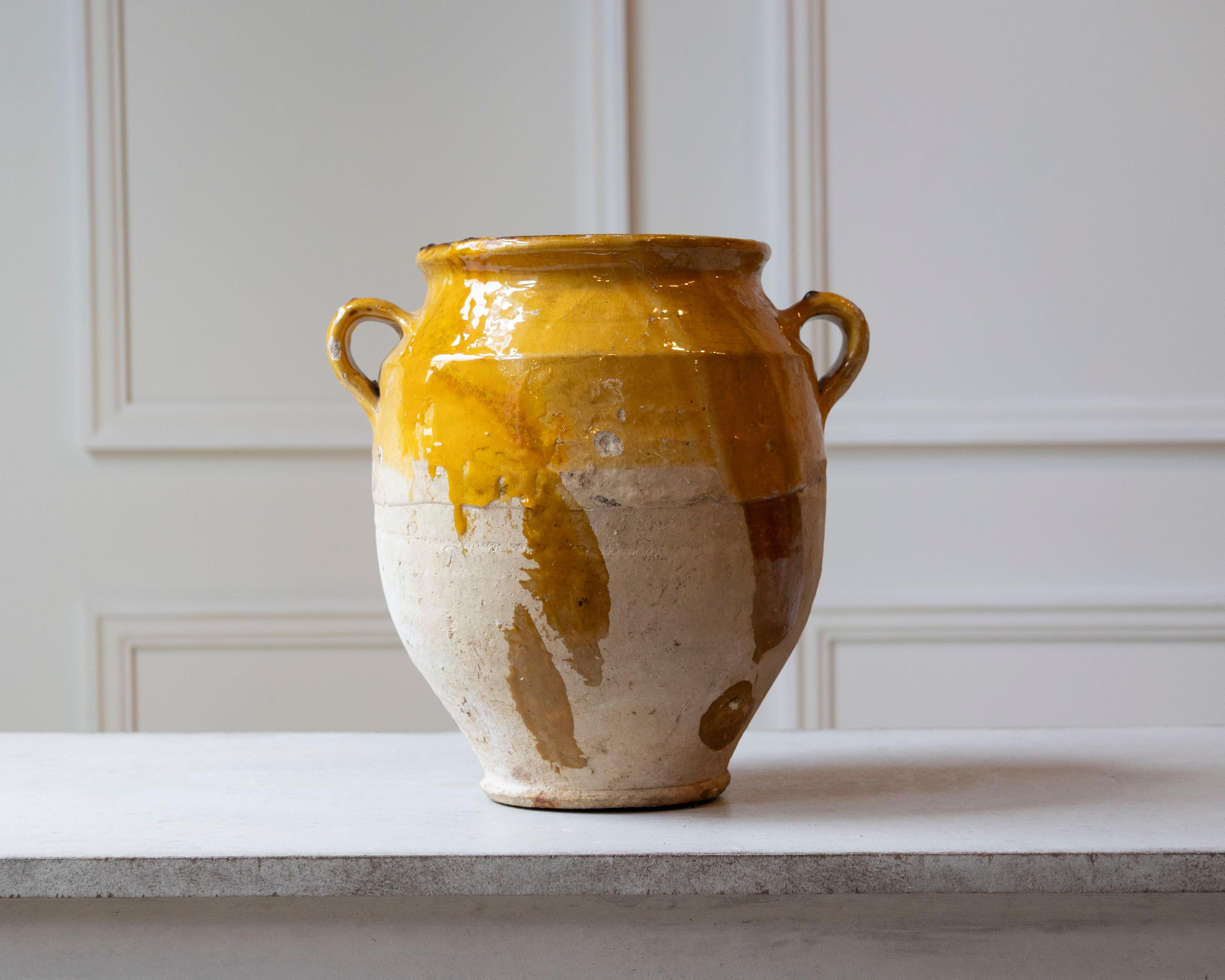 Dieser französische Confit-Topf aus dem 19. Jahrhundert ist ein strahlendes Beispiel für alltägliche bäuerliche Töpferware, die durch Zeit und Patina aufgewertet wurde. Dieses aus Südfrankreich stammende, handgegossene Terrakotta-Gefäß weist im