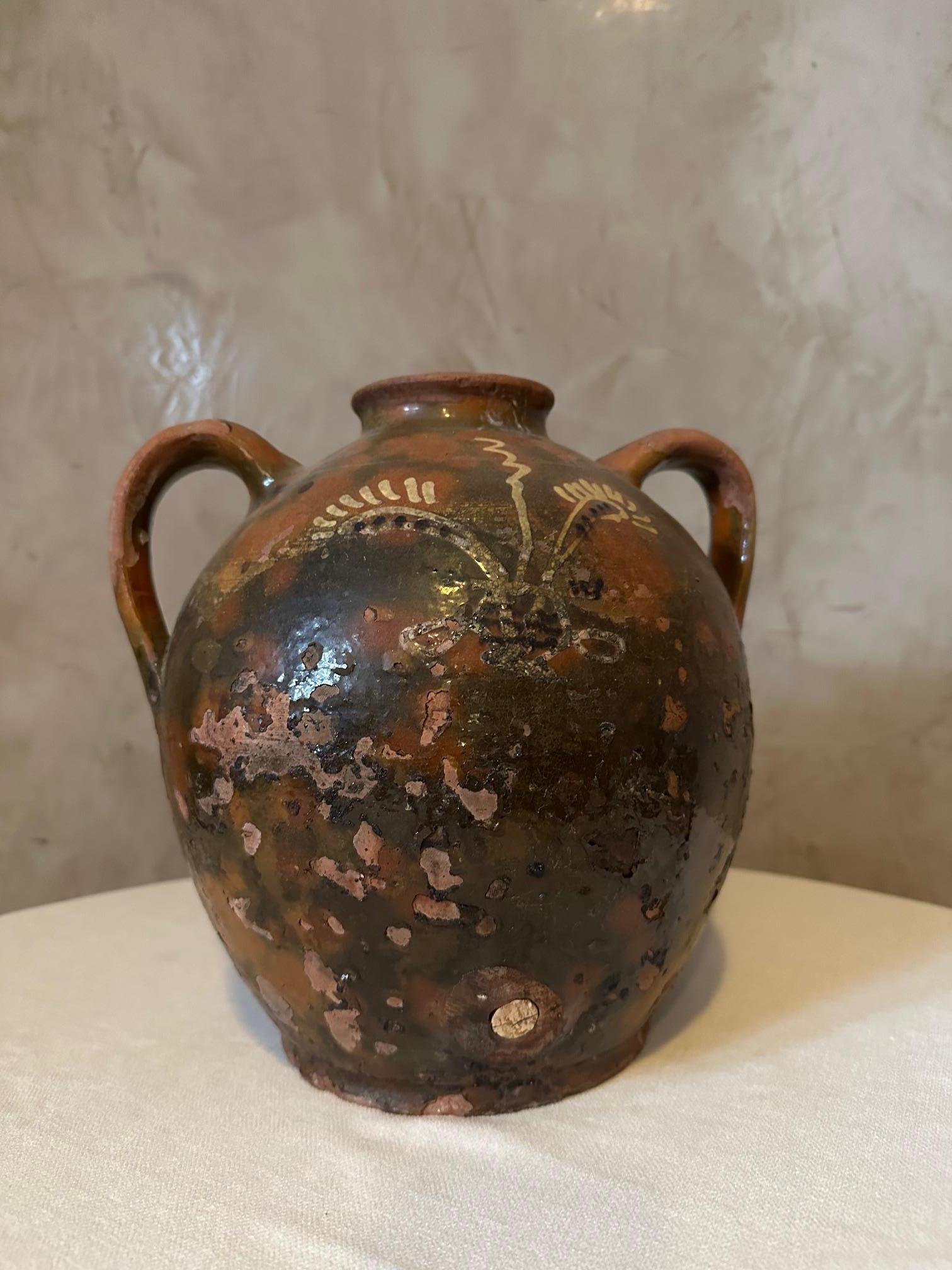 Very Nice rustic French glazed terracotta oil jug from the 19th century, with wavy lines and nicely distressed appearance. 
Created in France during the 19th century, this glazed terracotta pottery piece features a brown circular body accented with
