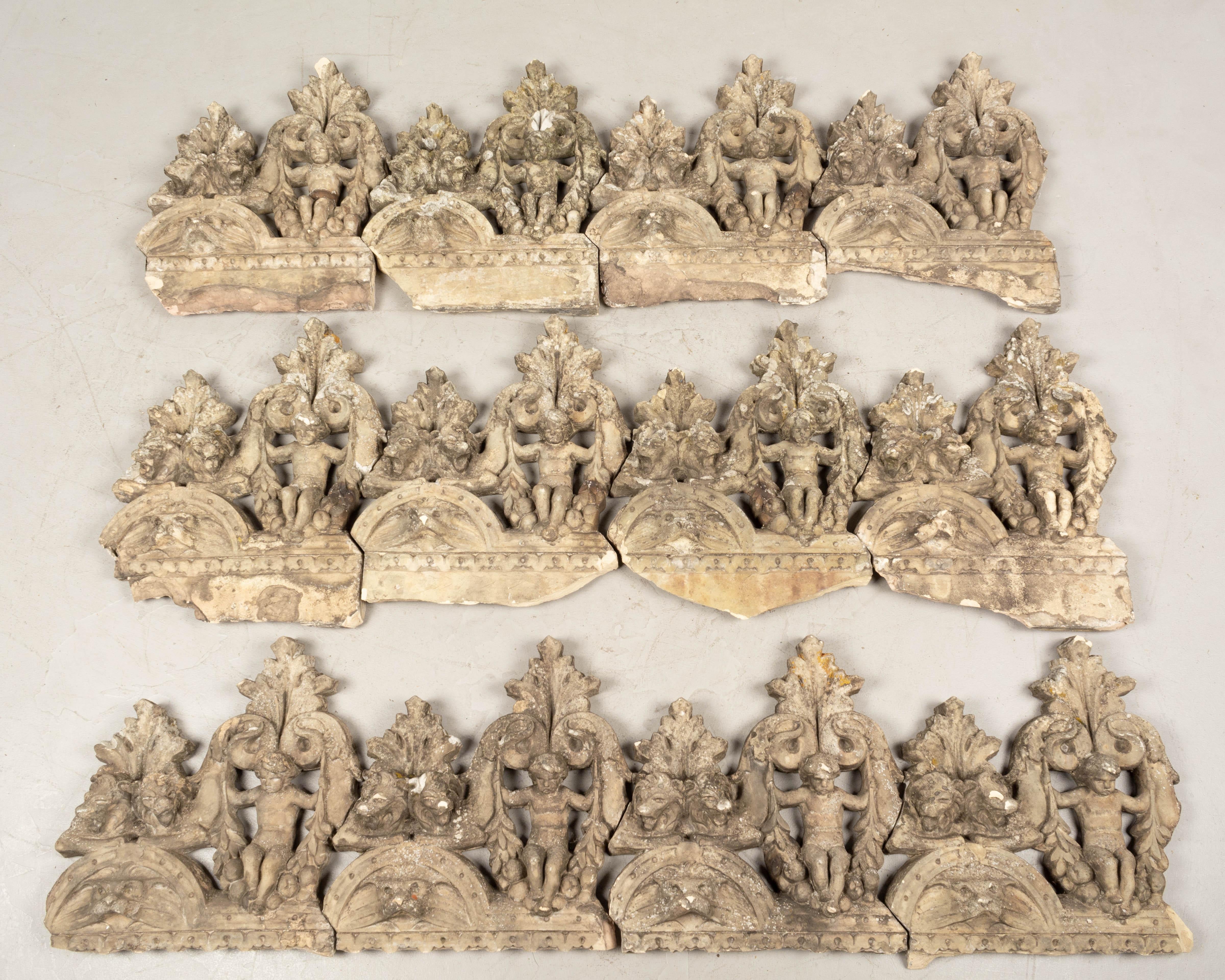 A set of twelve 19th century French terracotta garden tiles. Very large detailed casting of cupid with foliate details and lion heads. Rare form and scale. For use as border decoration, these tiles fit closely together and have a nice old mossy