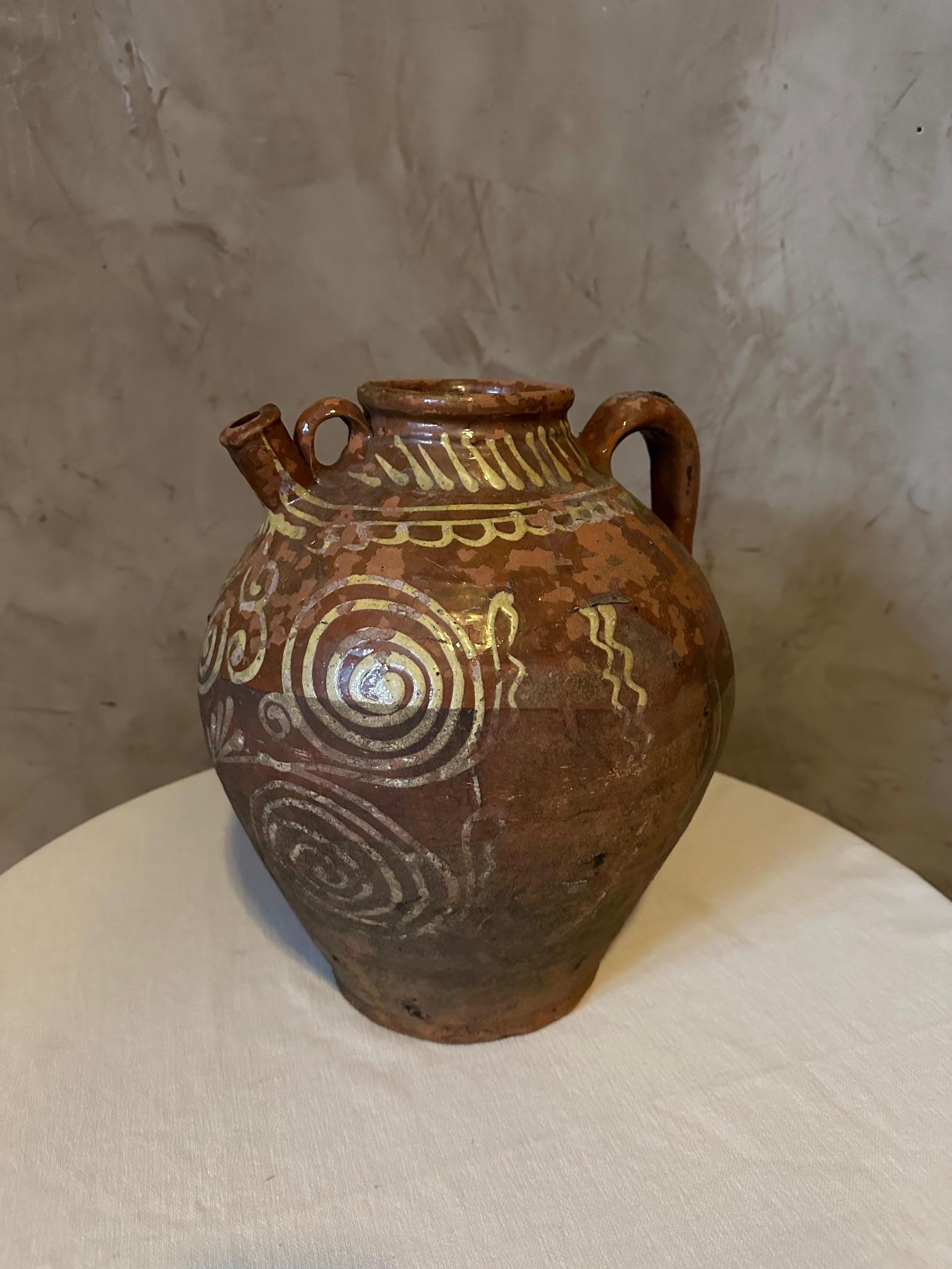 Very Nice rustic French glazed terracotta oil jug from the 19th century, with wavy lines and nicely distressed appearance. 
Created in France during the 19th century, this glazed terracotta pottery piece features a brown circular body accented with