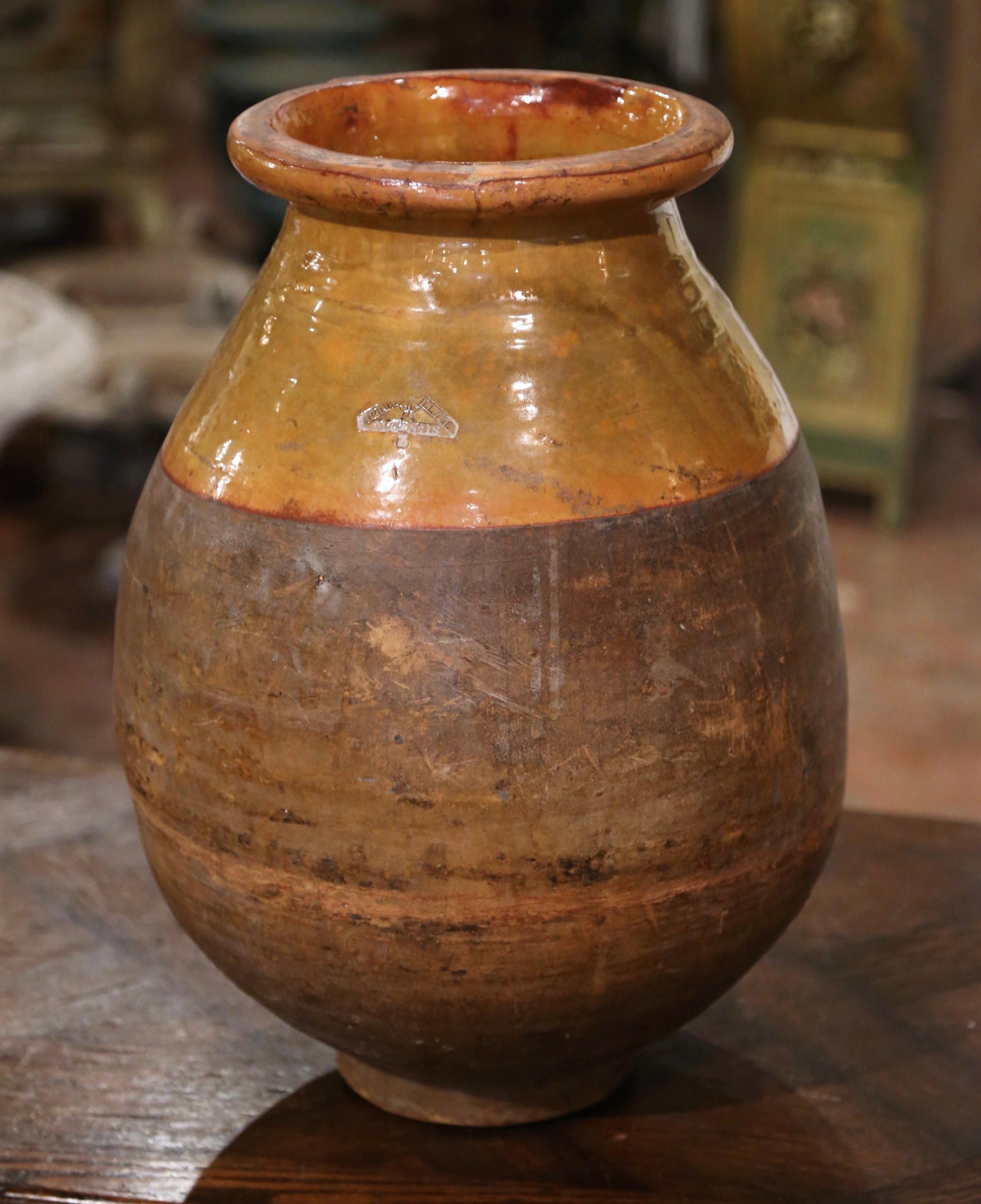 Dieser antike Olivenölkrug aus Steingut wurde um 1880 in Südfrankreich hergestellt. Die Terrakotta-Vase aus blondem Ton ist neutral in der Farbe und hat eine traditionelle runde Form. Die rustikale, von der Zeit gezeichnete Kanne weist eine gelbe