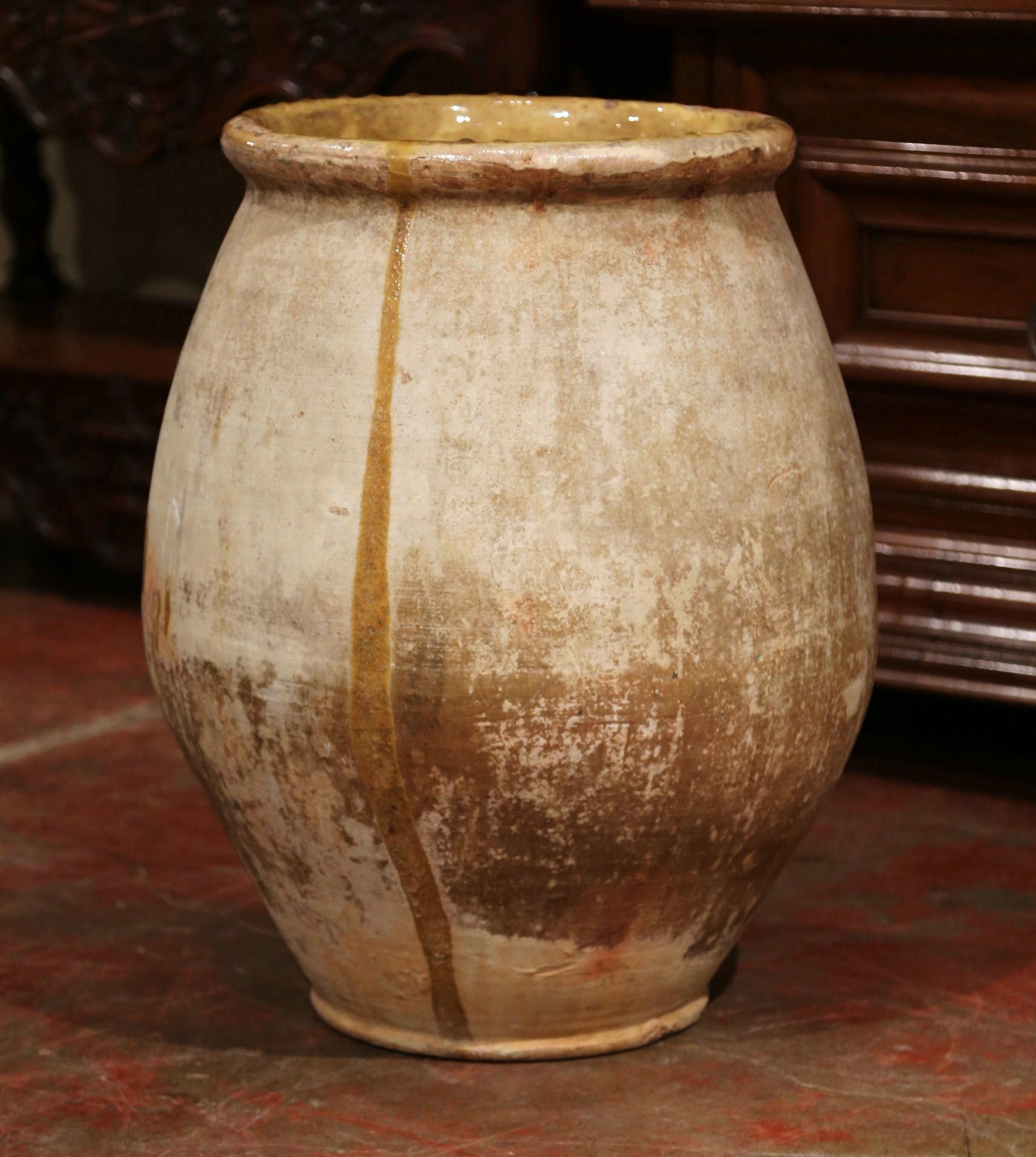 This large, antique earthenware olive jar was created in Southern France, circa 1870. Round in shape and made of blond clay, the terracotta pot features a yellow glaze around the neck and rim, and has a natural beige tone throughout the body.
