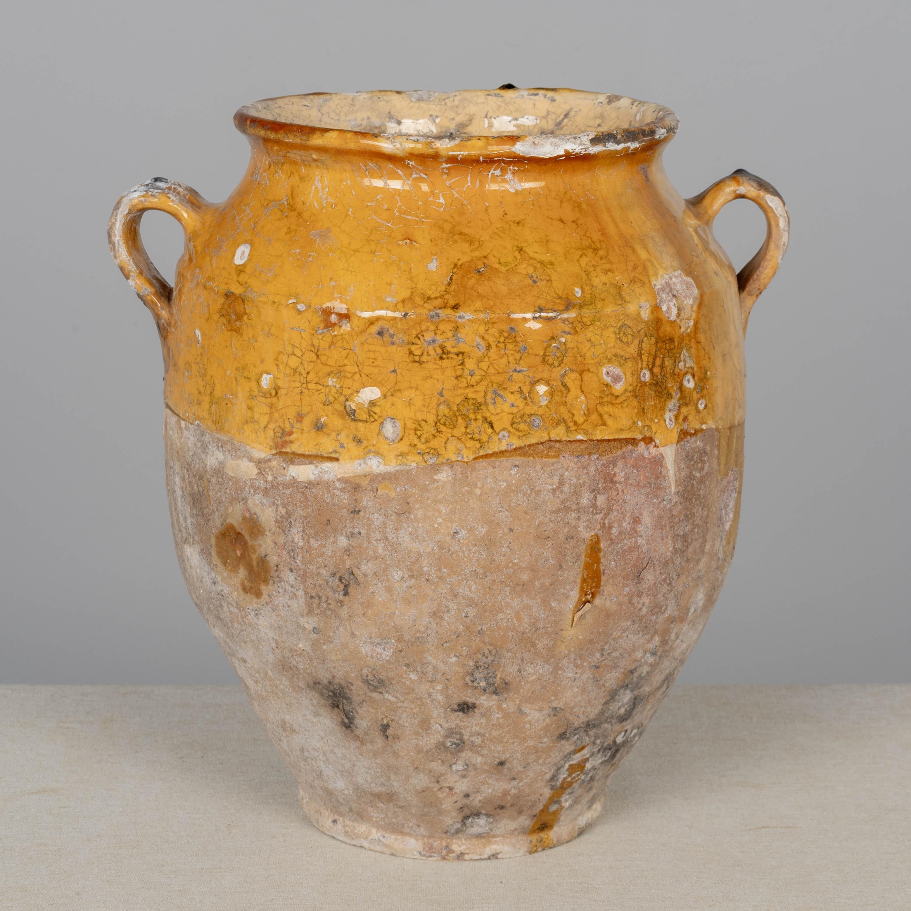 A 19th century French earthenware pot à confit with traditional yellow glaze. Rustic condition with crackled glaze, some chips and losses to glaze. These ordinary earthenware vessels were once used daily in the French country home and have beautiful