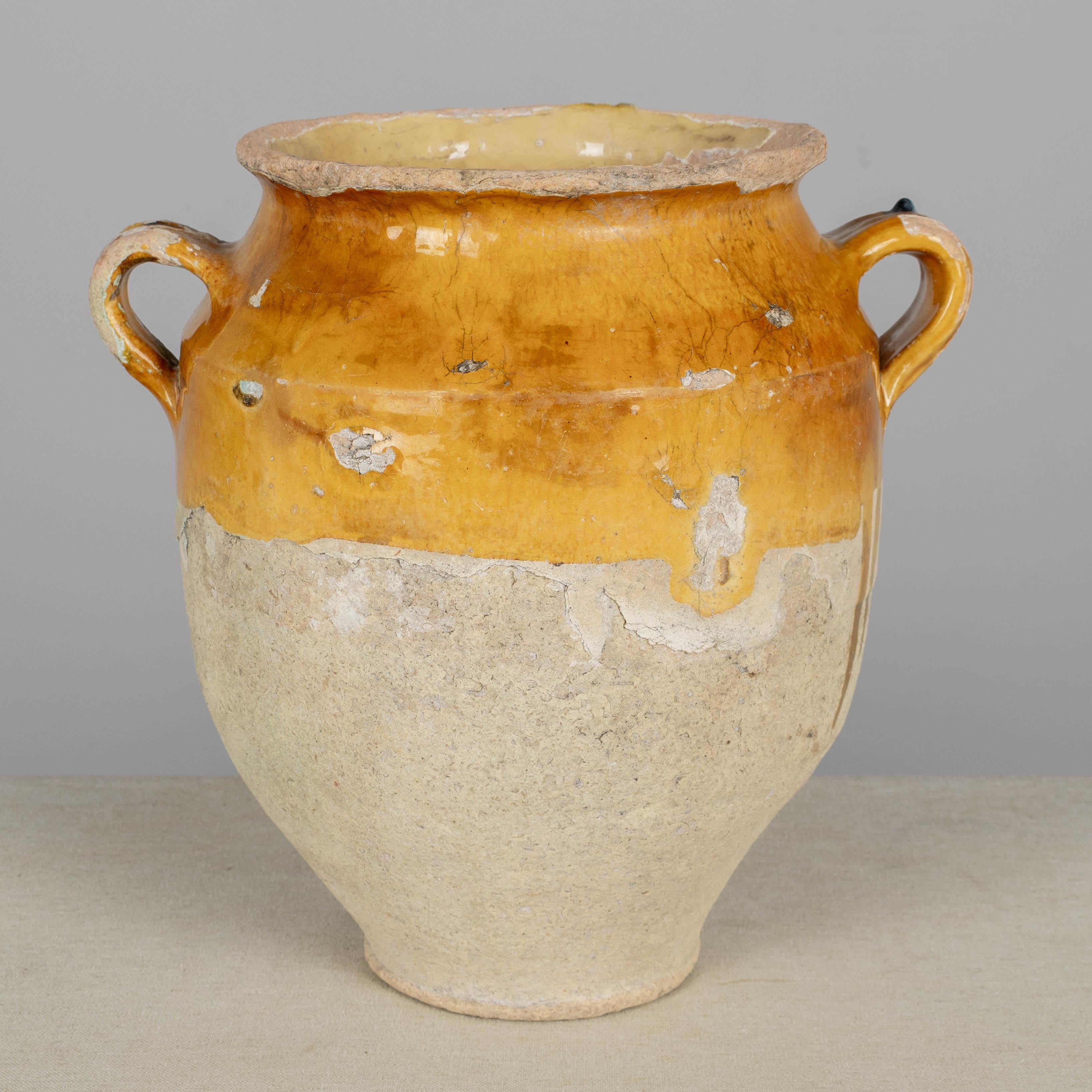 A 19th century French earthenware pot à confit with traditional yellow glaze. Rustic condition with crackled glaze, some chips and losses to glaze. These ordinary earthenware vessels were once used daily in the French country home and have beautiful