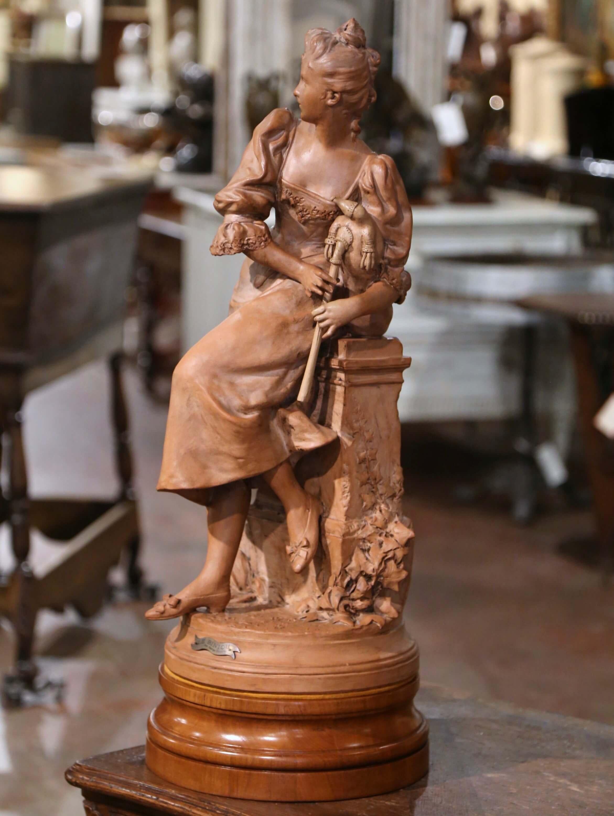 Décorez le bureau d'une dame ou une étagère de bibliothèque avec cette élégante figure antique. Sculptée en France vers 1890, la statue en terre cuite repose sur un socle en noyer séparé et représente une jeune femme jouant de la cornemuse.