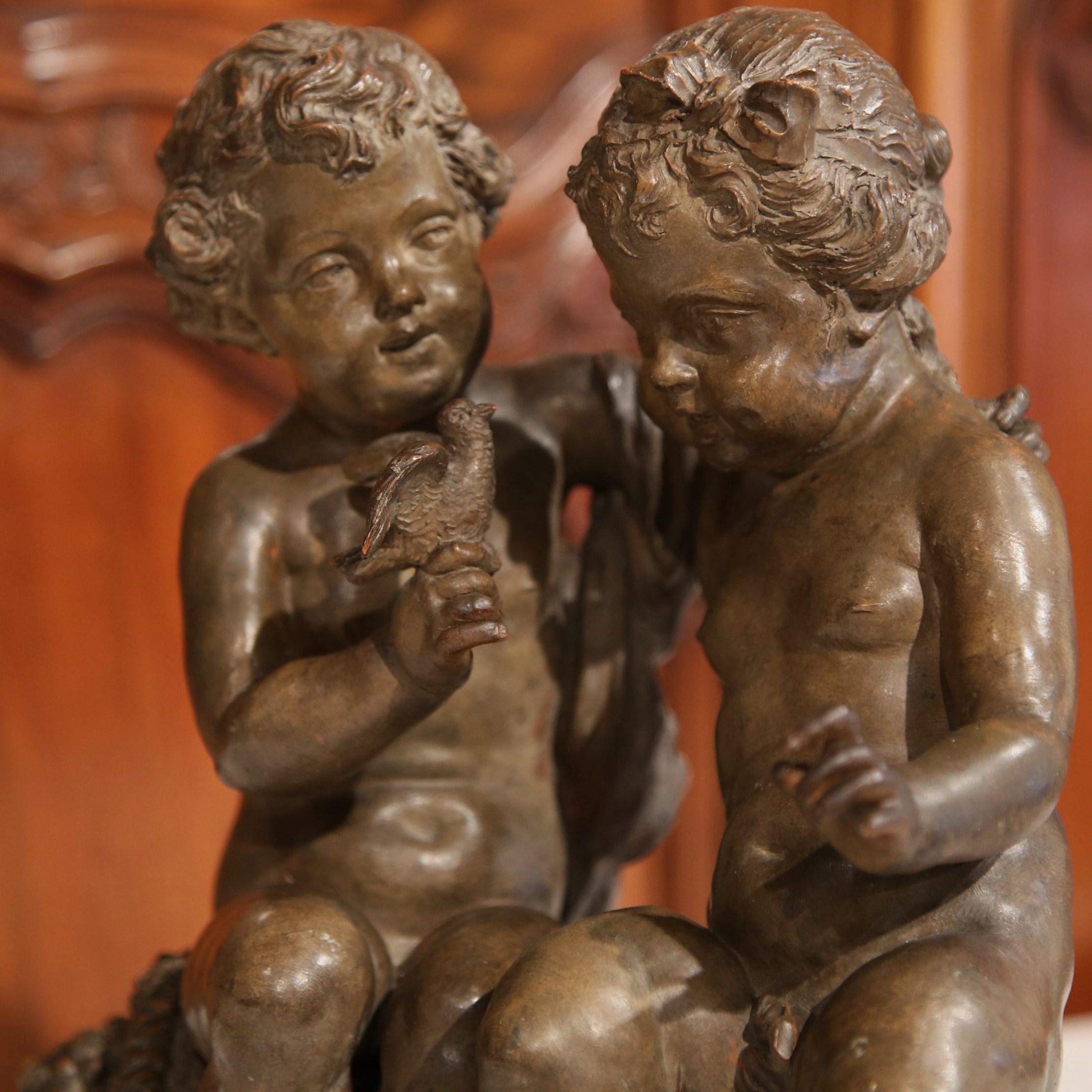 Questo affascinante gruppo antico in terracotta è stato scolpito a Parigi, in Francia, intorno al 1880. La composizione dettagliata raffigura due putti giocherelloni seduti insieme, uno dei quali tiene in mano un uccellino mentre l'altro ascolta con