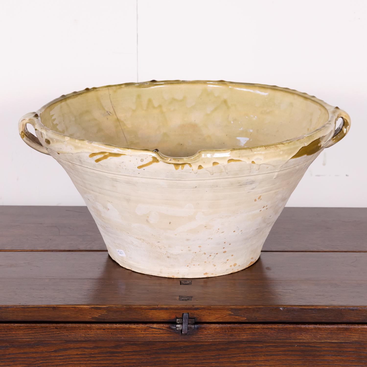 Lovely 19th century French tian bowl complete with both handles and pouring spout having an unglazed pale terracotta exterior and a beautiful pale yellowish green glaze to the interior and lip. Tian bowls, which are basically earthenware mixing