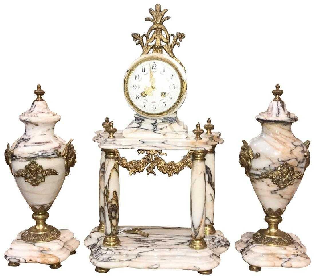 Exquisite 19th century French three-piece clock set. The veined marble clock with four columns, flame finials and mounted with finely detailed bronze appliques of festoon swags and caryatid masques. The clock is flanked by similarly decorated ovoid