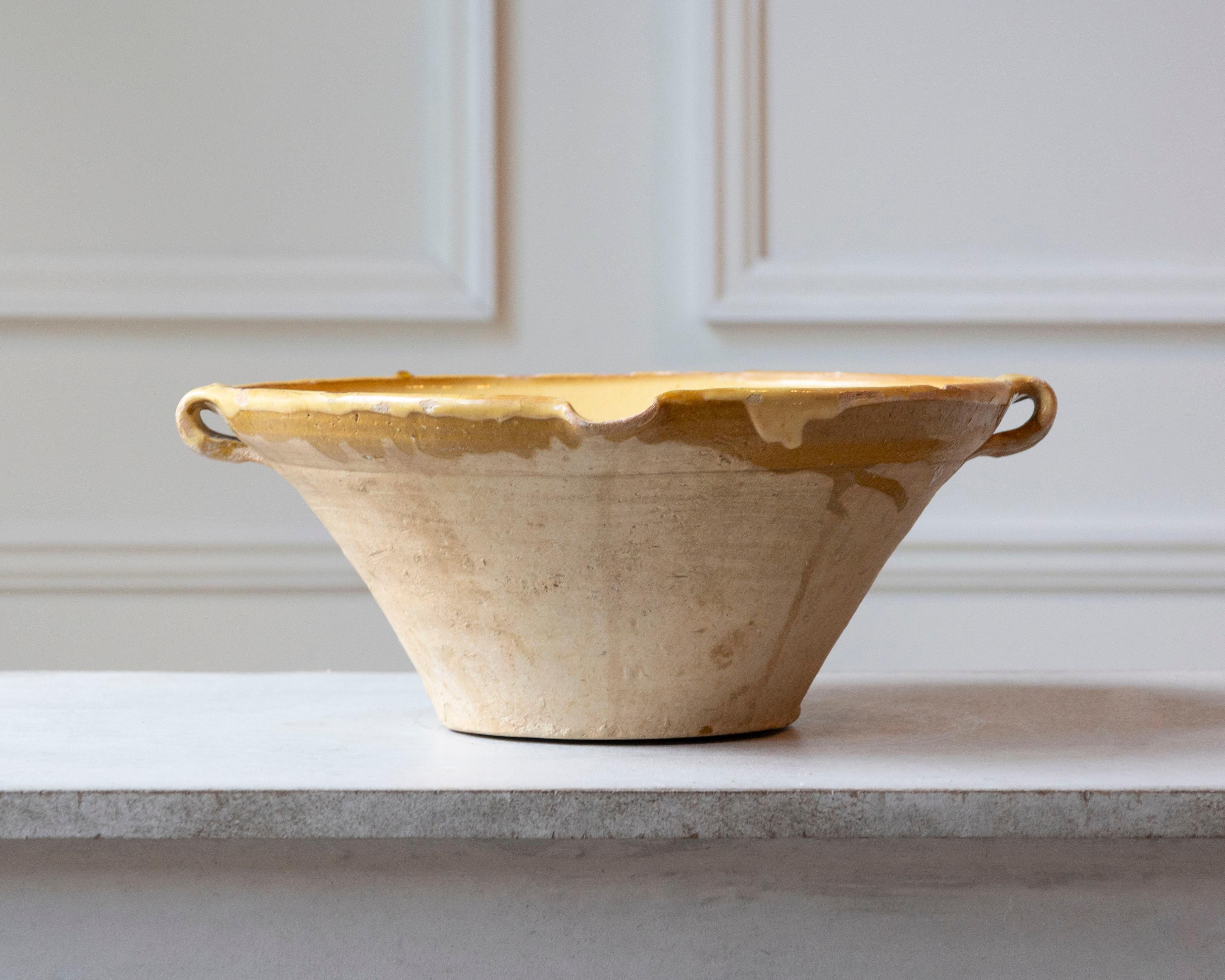 This 19th-century French Tian bowl is a classic example of rustic Provençal pottery, once an essential kitchen vessel in southern France. Handcrafted from terracotta, the bowl features a wide, shallow form with sloping sides and sturdy loop handles,