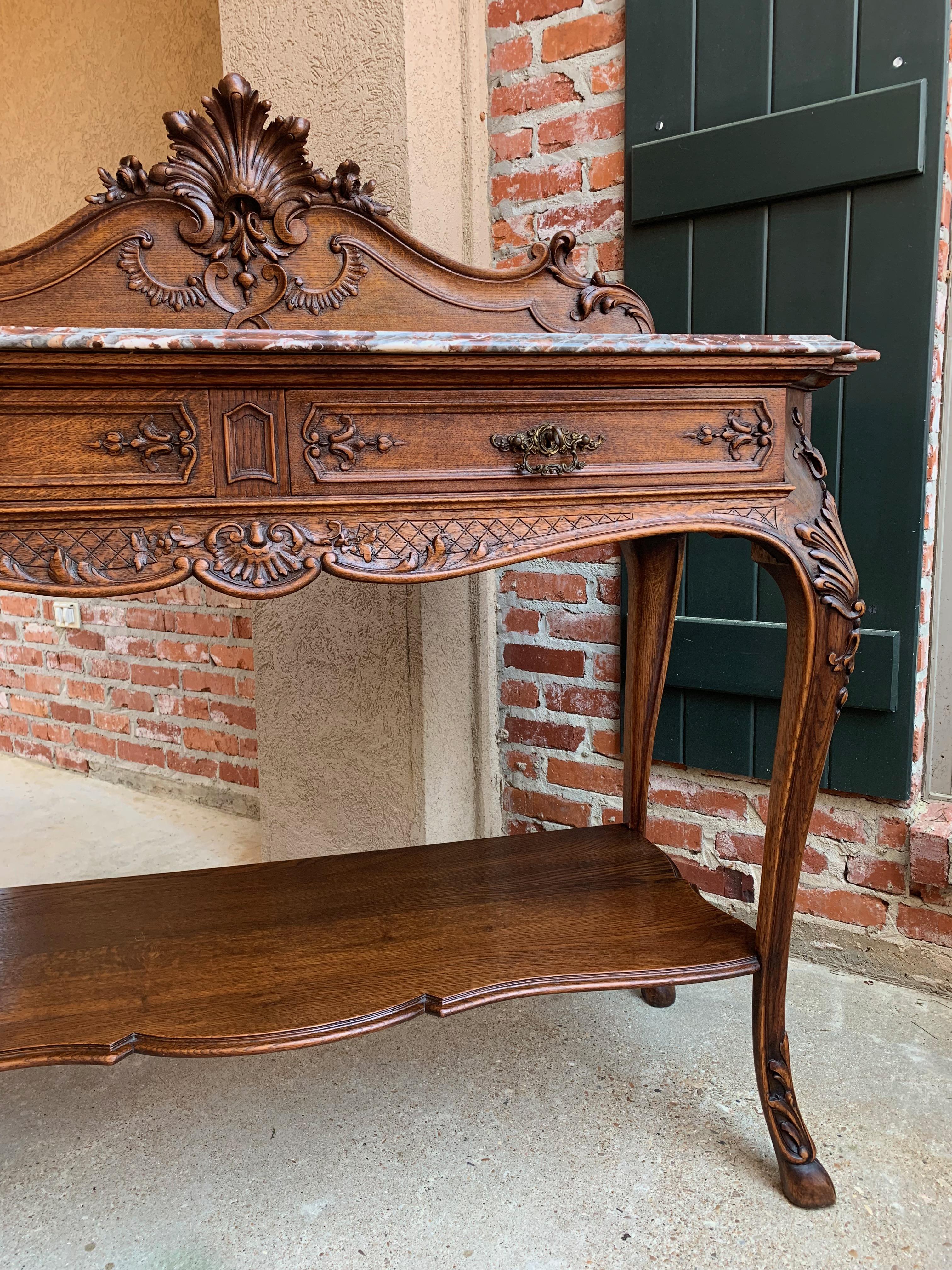 Direct from France, a lovely antique French carved oak sideboard or buffet in classic Louis XV style.
~Beautiful French carvings throughout, with a tall raised paneled back with dimensional French cartouche center with serpentine edges~
~Two