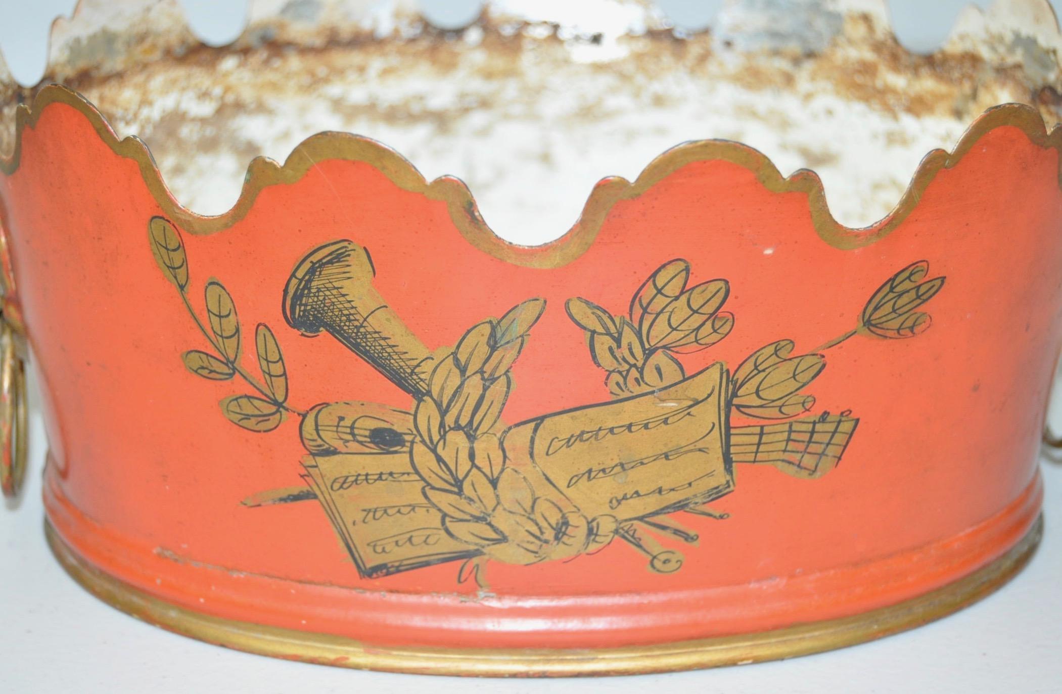 Lovely 19th century French Toleware Vierriere

Scalloped border with a crimson body accented with a musical themed gilt medallion, and lion head handles.

Dimensions 9 1/2