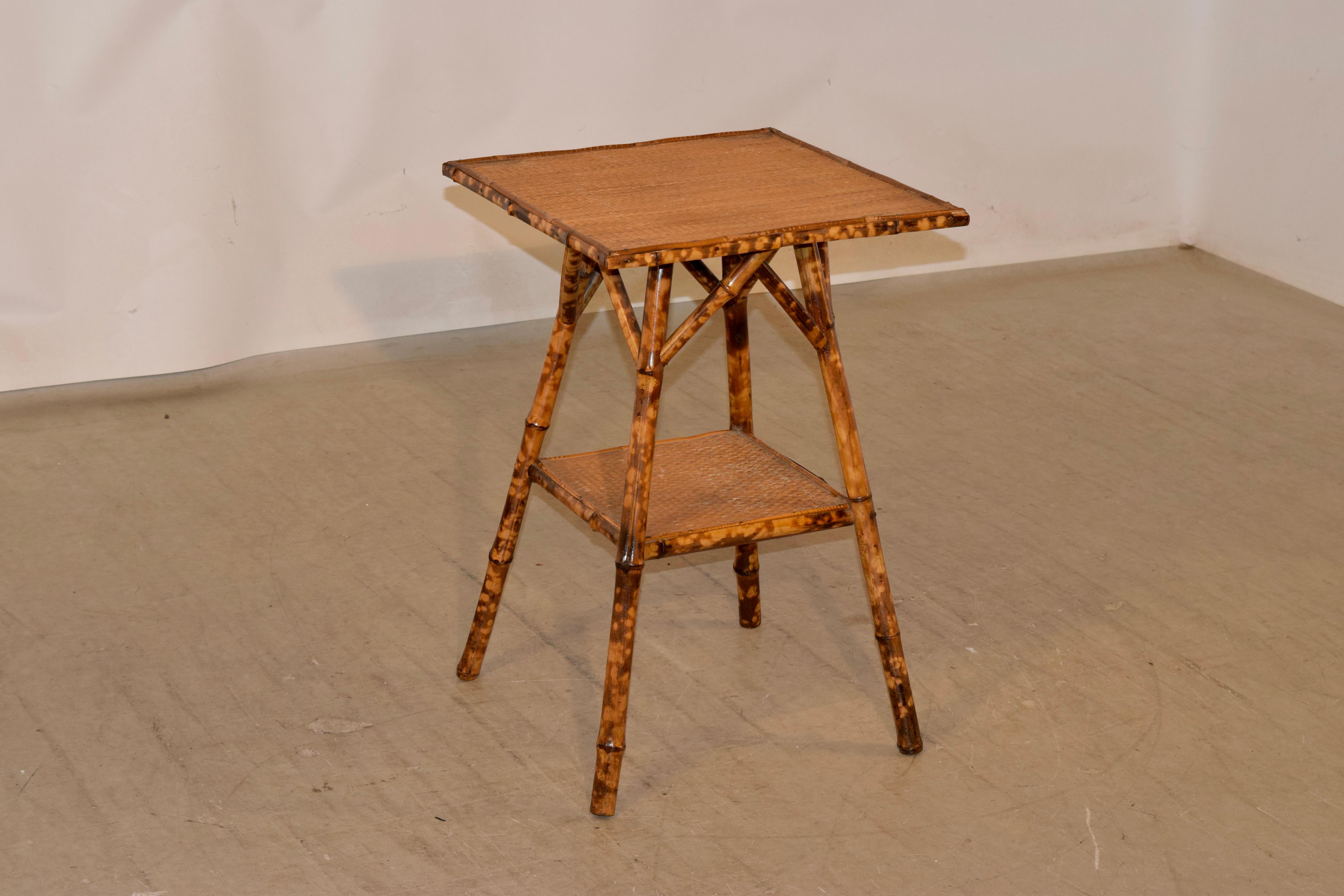 19th century tortoise bamboo table from France with a rush covered top and slightly splayed legs, joined by a lower shelf, which is also covered in rush.