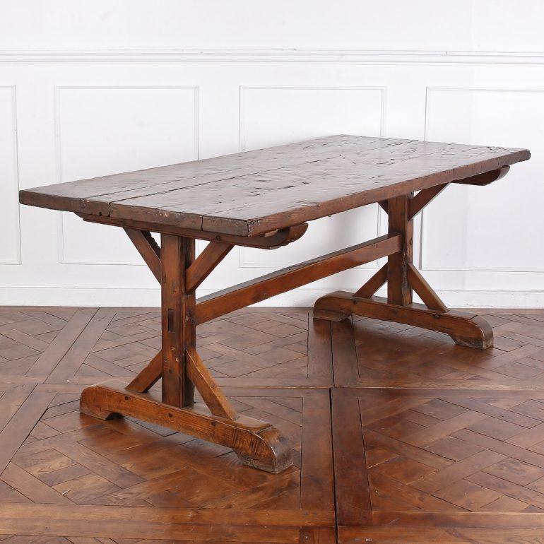 A 19th century French solid oak trestle table with a warm color and rustic patina, the legs with simple geometric angled braces and united by a long oak stretcher. 
  