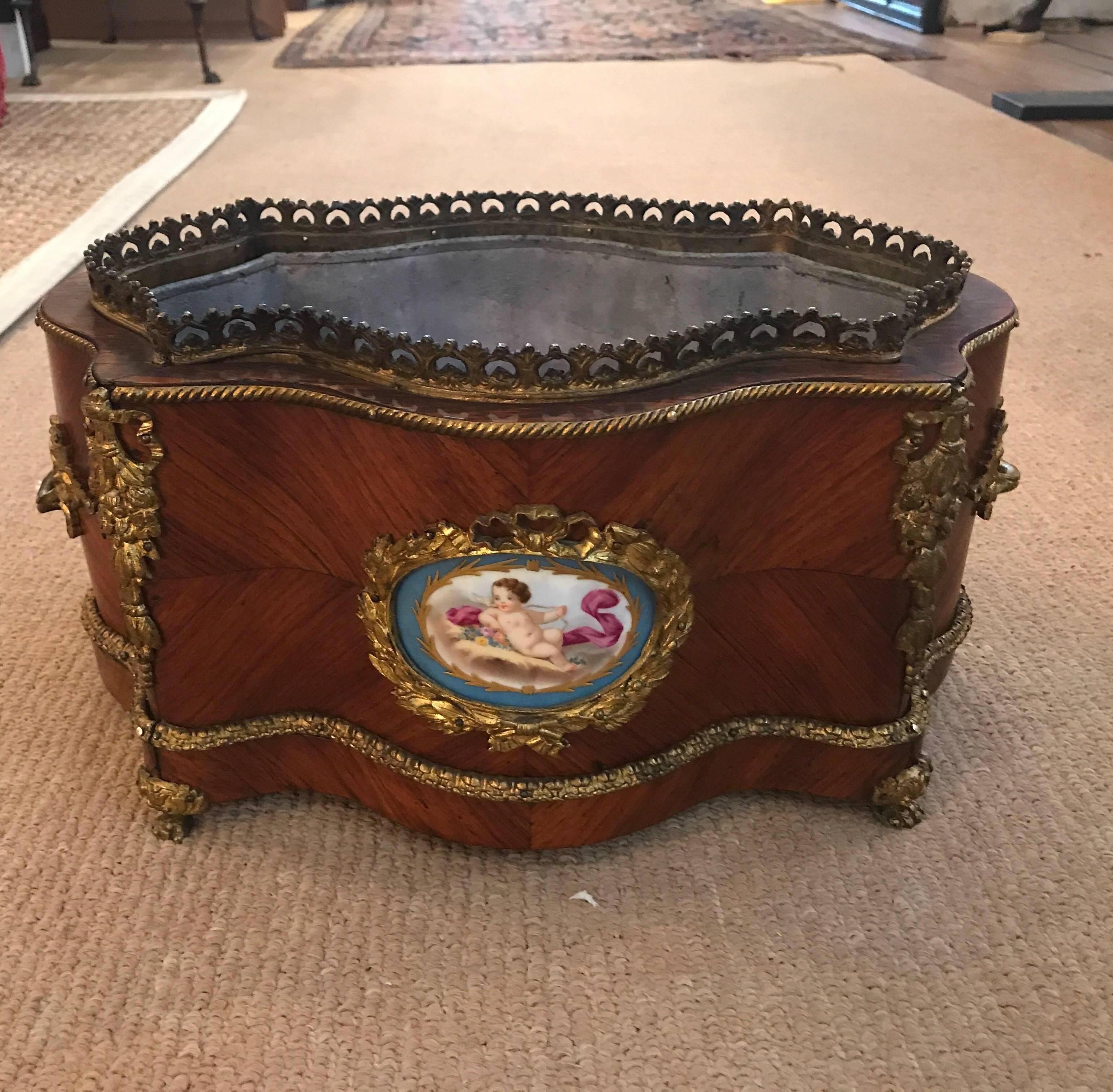 A 19th century tulipwood jardinière with tin liner. The bookmatched tulip wood background with porcelain hand painted Sèvres style cartouches with ormolu mounts, France, circa 1880.