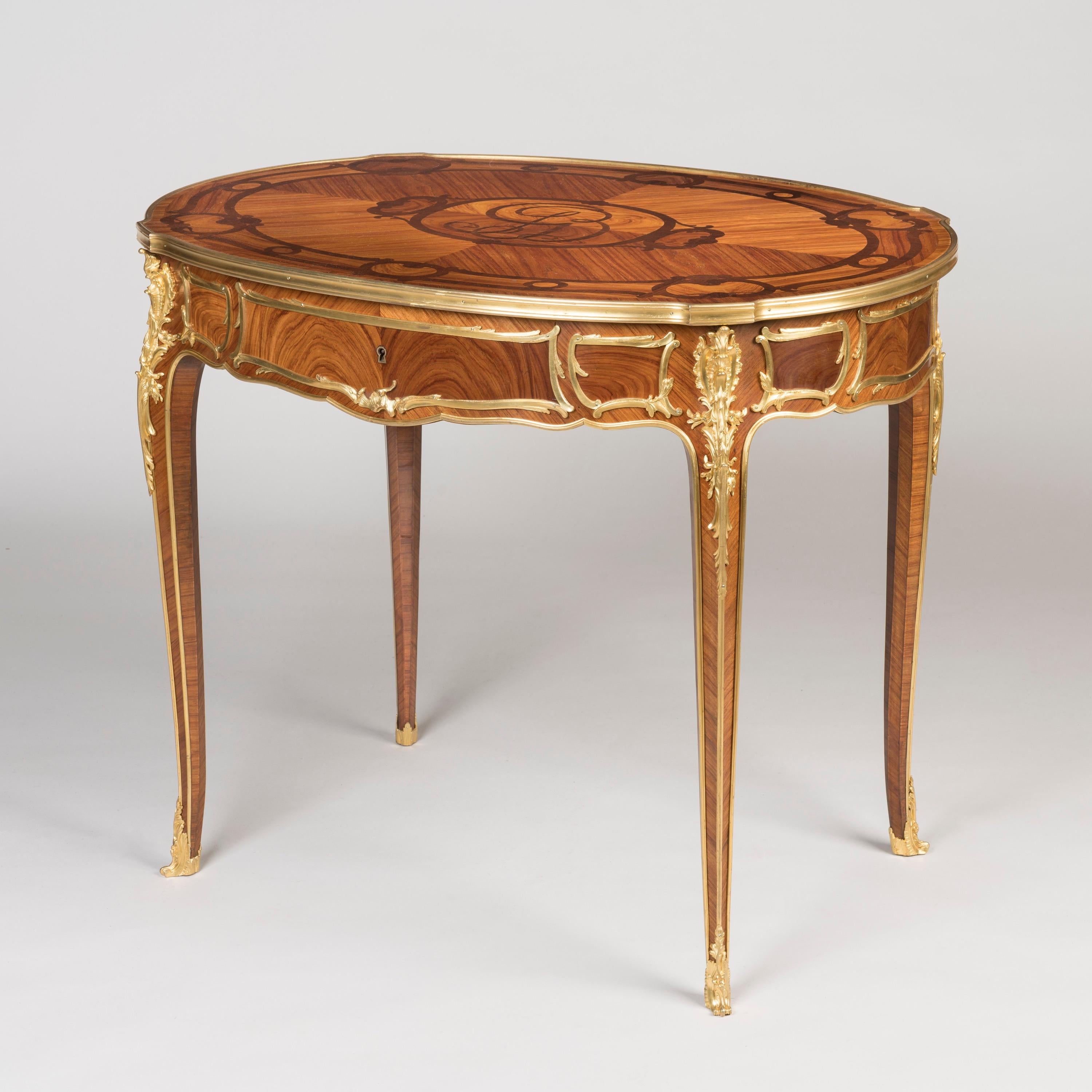 An Elegant Tulipwood Table
In the Louis XVI Style

Veneered in a beautifully figured tulipwood with a contrasting kingwood inlay and decorated with mercury gilt bronze mounts; the oval table supported on slender cabriole legs with ormolu sabots
