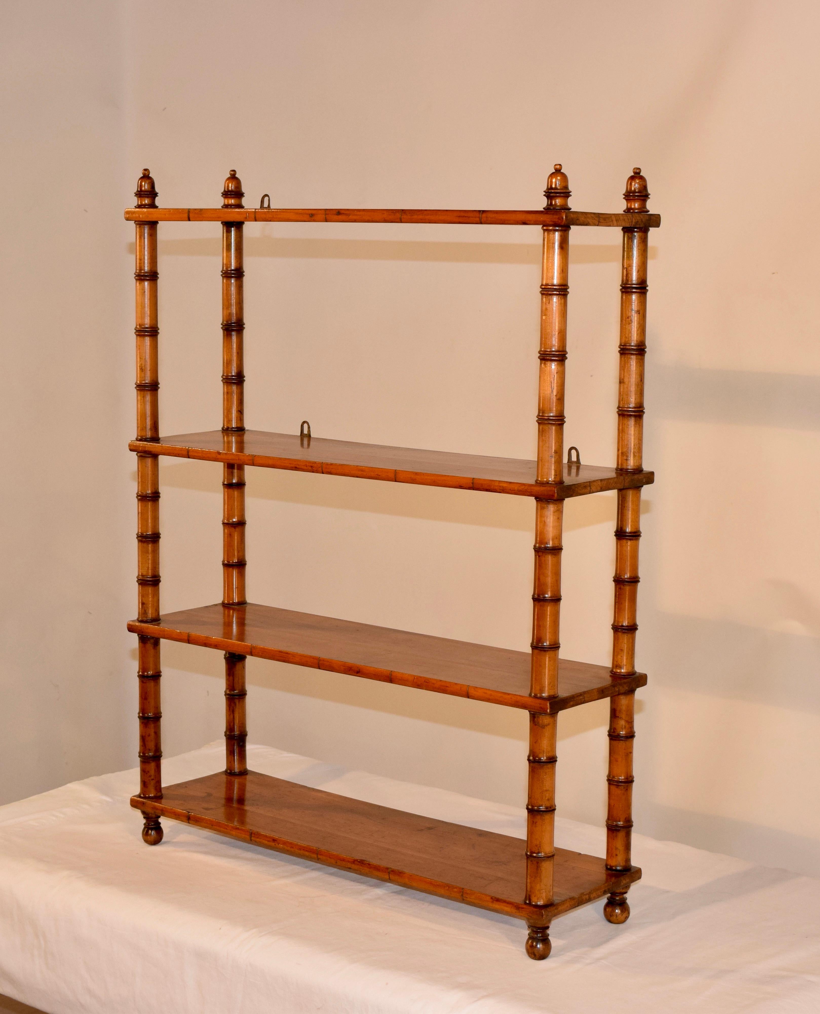 19th century cherry wall shelf from France with hand-turned finials and shelf supports and four shelves. Supported on hand-turned feet. Shelf has hanging hardware but can be used as a standing shelf if desired.