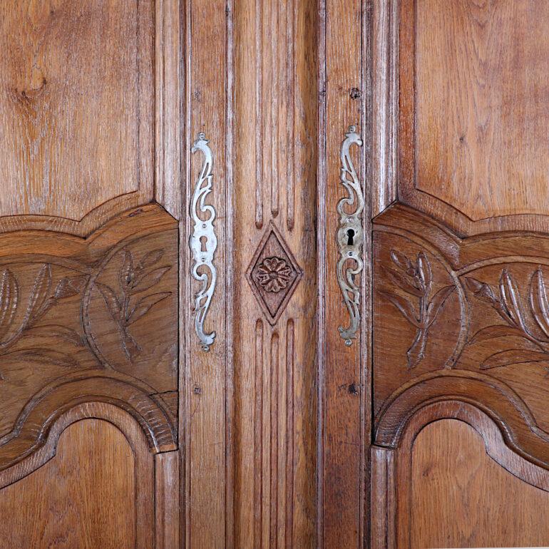 A 19th century French carved oak two-door armoire with decorative carving. The doors have beautiful shaped panels with molded frames and feature hand carved floral details. Further carving to crown and base, and raised on shaped cabriole legs.