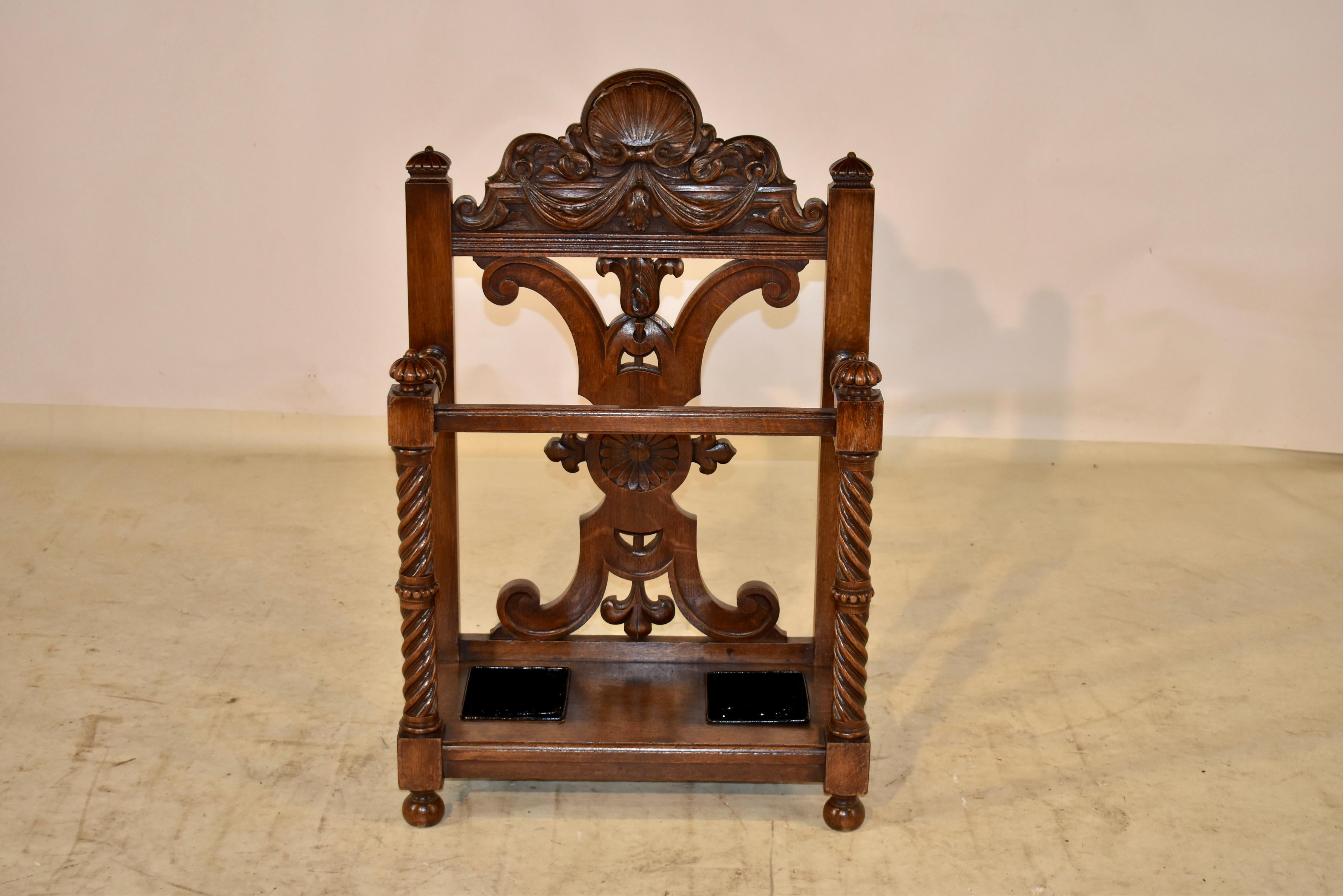 19th century oak umbrella stand from France. This umbrella stand has wonderful hand carved decorative detail throughout. The back has a shell over a carved swag, following down to a carved and shaped back flanked on either side by a post and finial