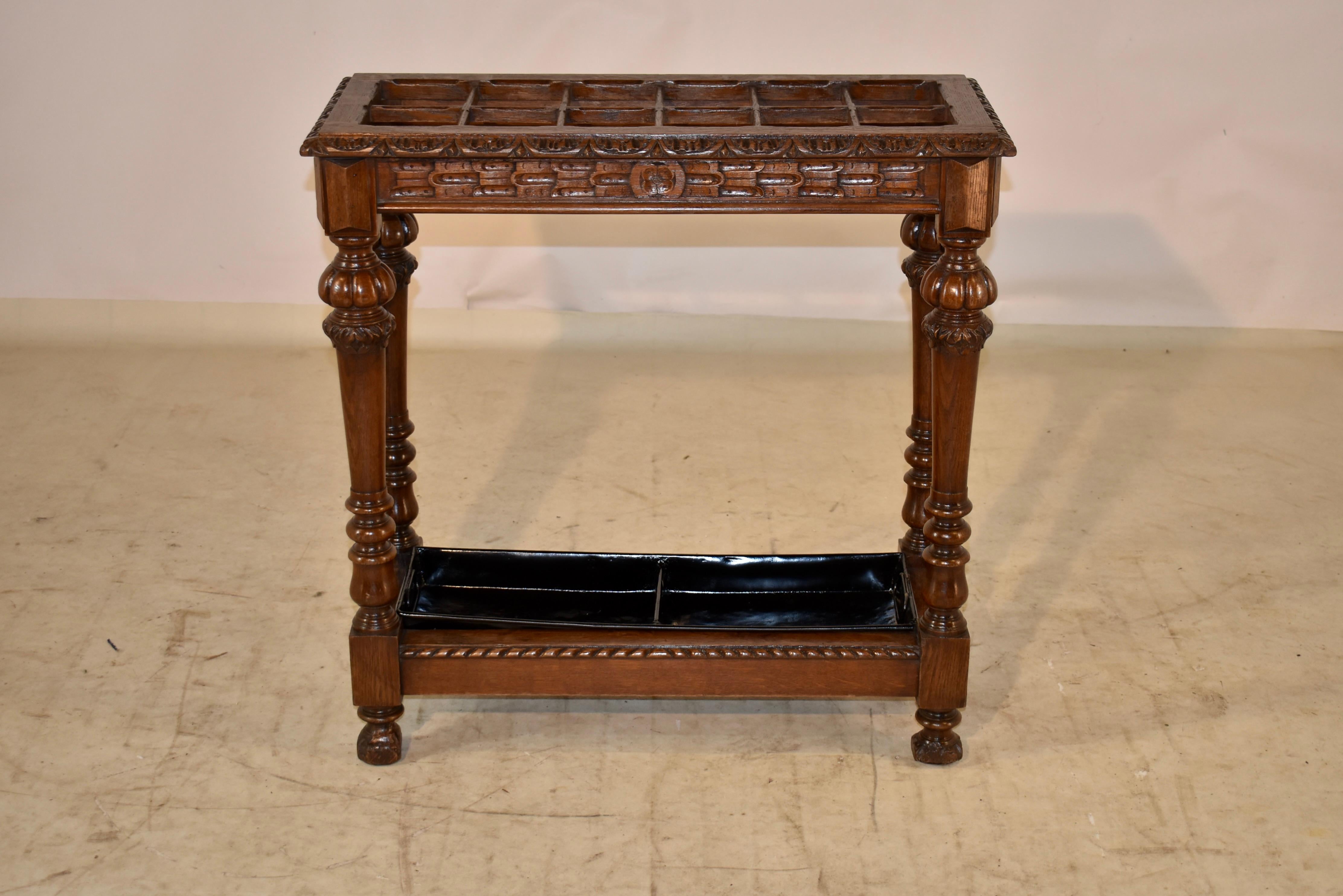 19th century oak umbrella stand from France with a beveled and carved decorated edge around the top, surrounding twelve sections for umbrellas or canes. The apron is wonderfully carved decorated as well and the piece is supported on hand turned