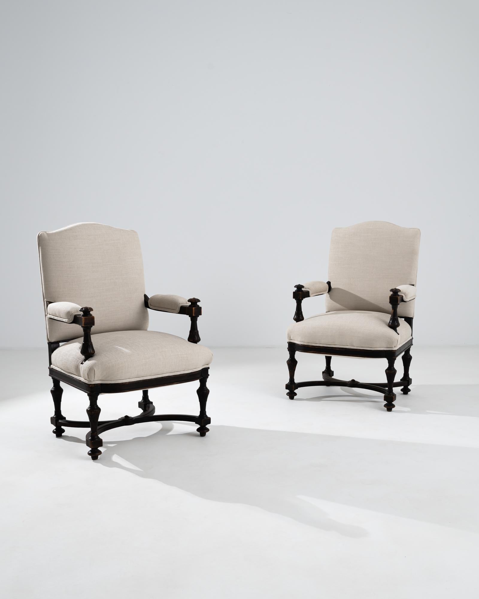 A pair of hardwood armchairs with upholstered seats and backrests from France, circa 1860. A warm and pleasing glow emits from the dark brown wood that composes these elegant chairs. The throne-like frame is embellished with elaborate carving,