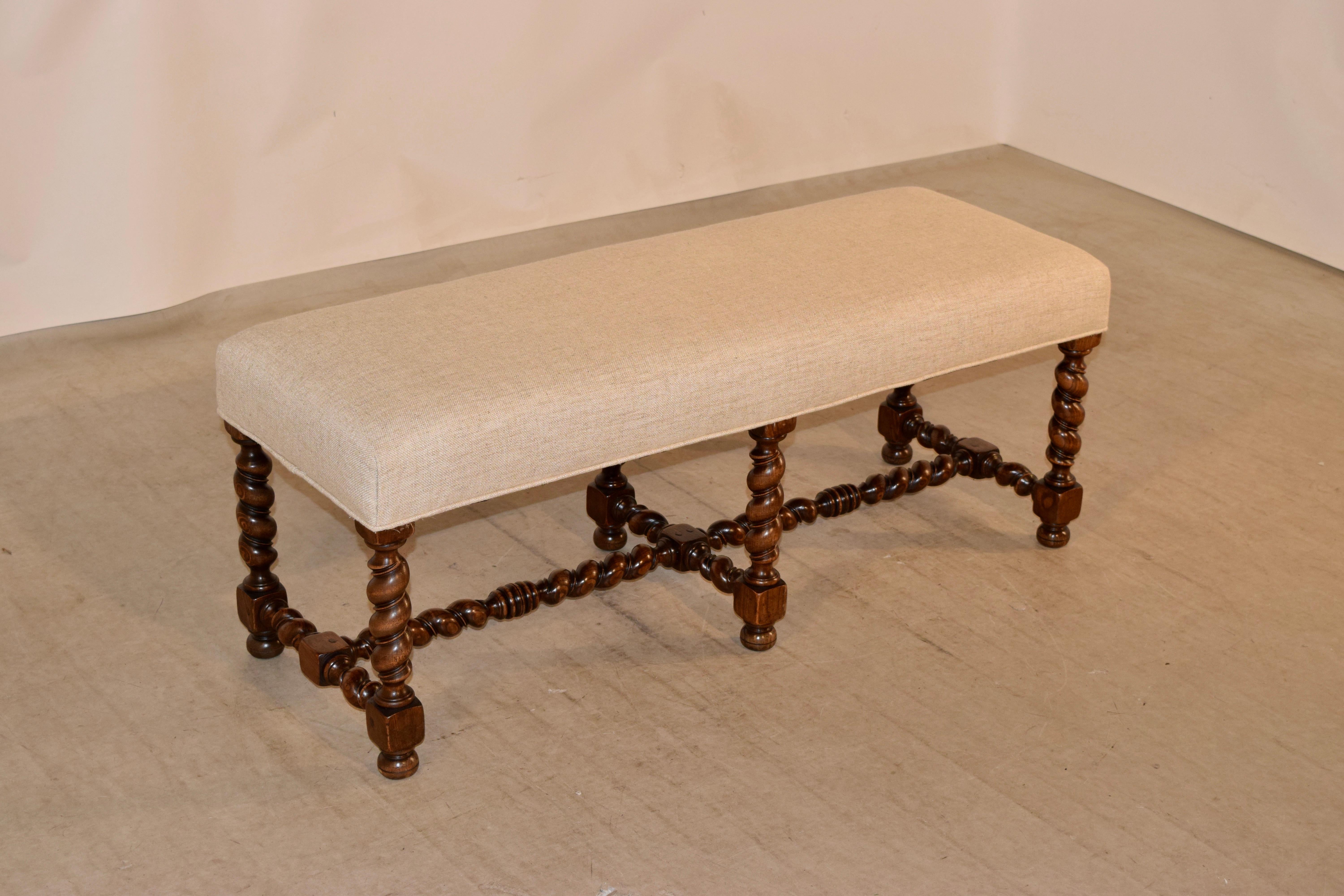 19th century upholstered bench from France with a newly upholstered seat in linen with single welt decoration. The frame is made from walnut, and the legs are hand-turned vine twist, which are fantastic and much more unusual than barley twist. The