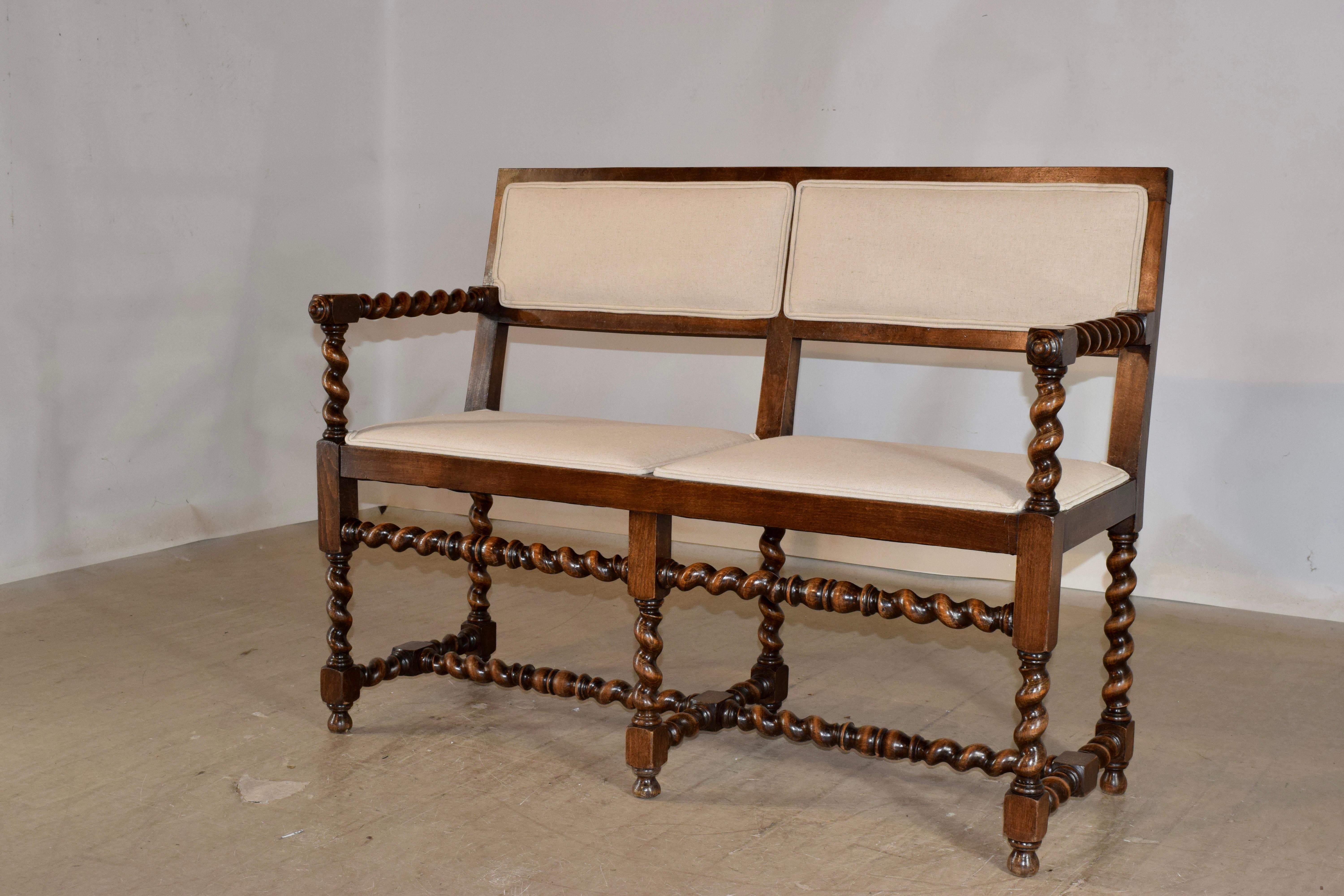 19th century oak bench from France with newly upholstered seat and back. The frame is lovely and solid and has beautifully hand turned barley twist arms, and the bench is supported on hand turned barley twist legs, joined by matching stretchers.