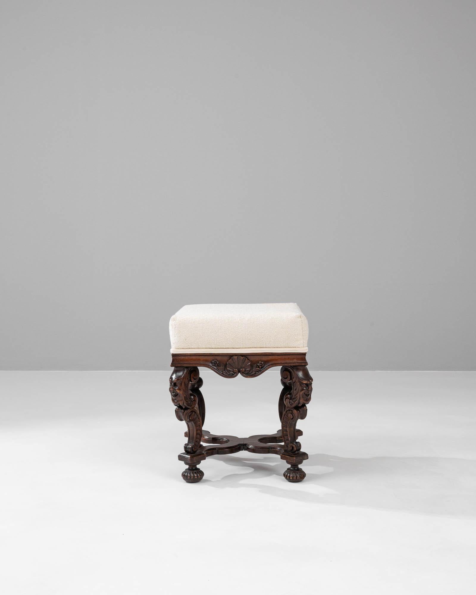 This 19th Century French upholstered stool is a delightful nod to the ornate and meticulous craftsmanship of the period. The dark, richly stained wood boasts expertly carved details, from the elegant scrollwork to the delicate floral accents, each
