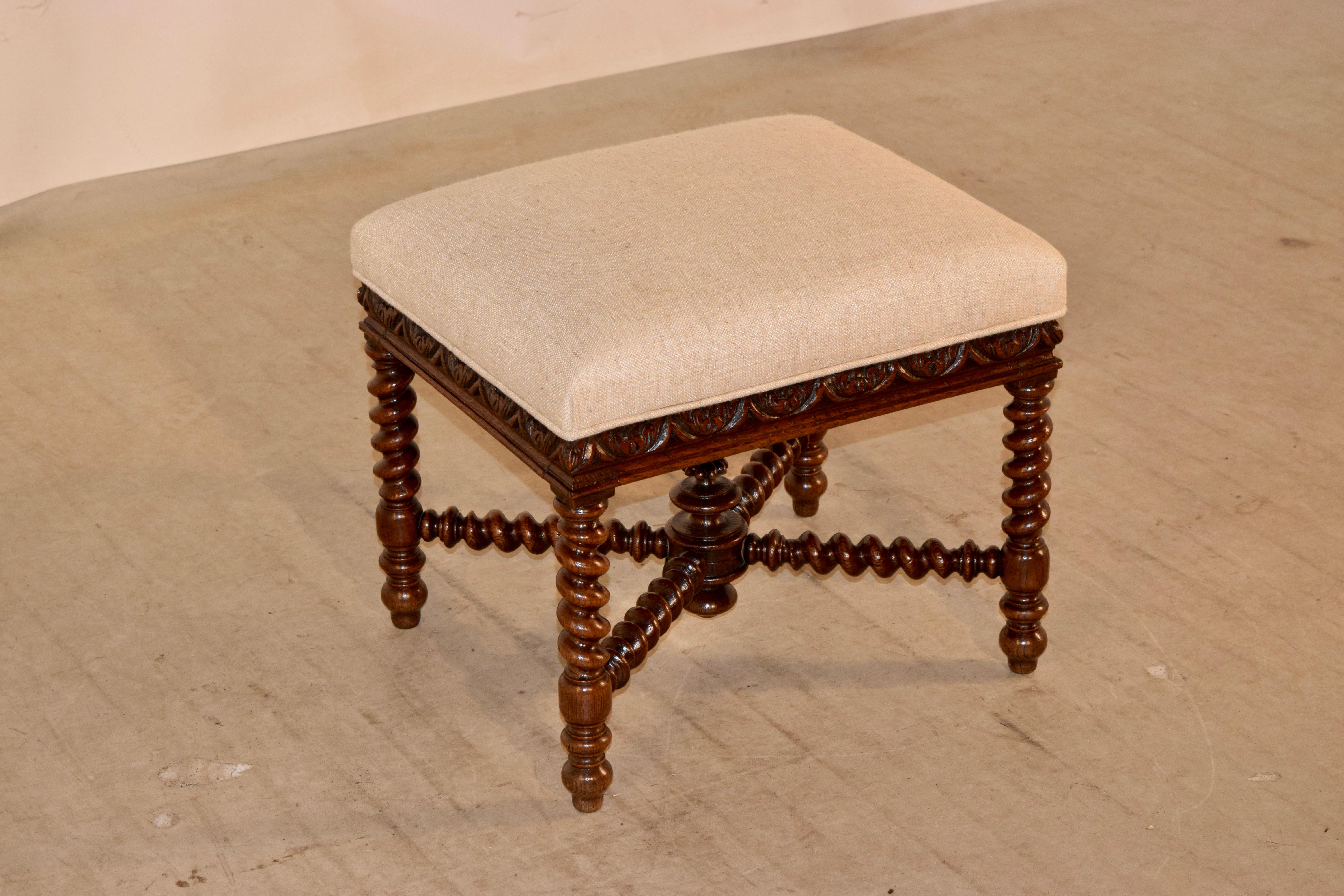 19th century oak stool from France with a newly upholstered seat in linen. The frame has wonderfully hand-turned barley twist legs and cross stretchers below a lovely hand carved and molded base to the seat. Finished with a hand-turned finial in the